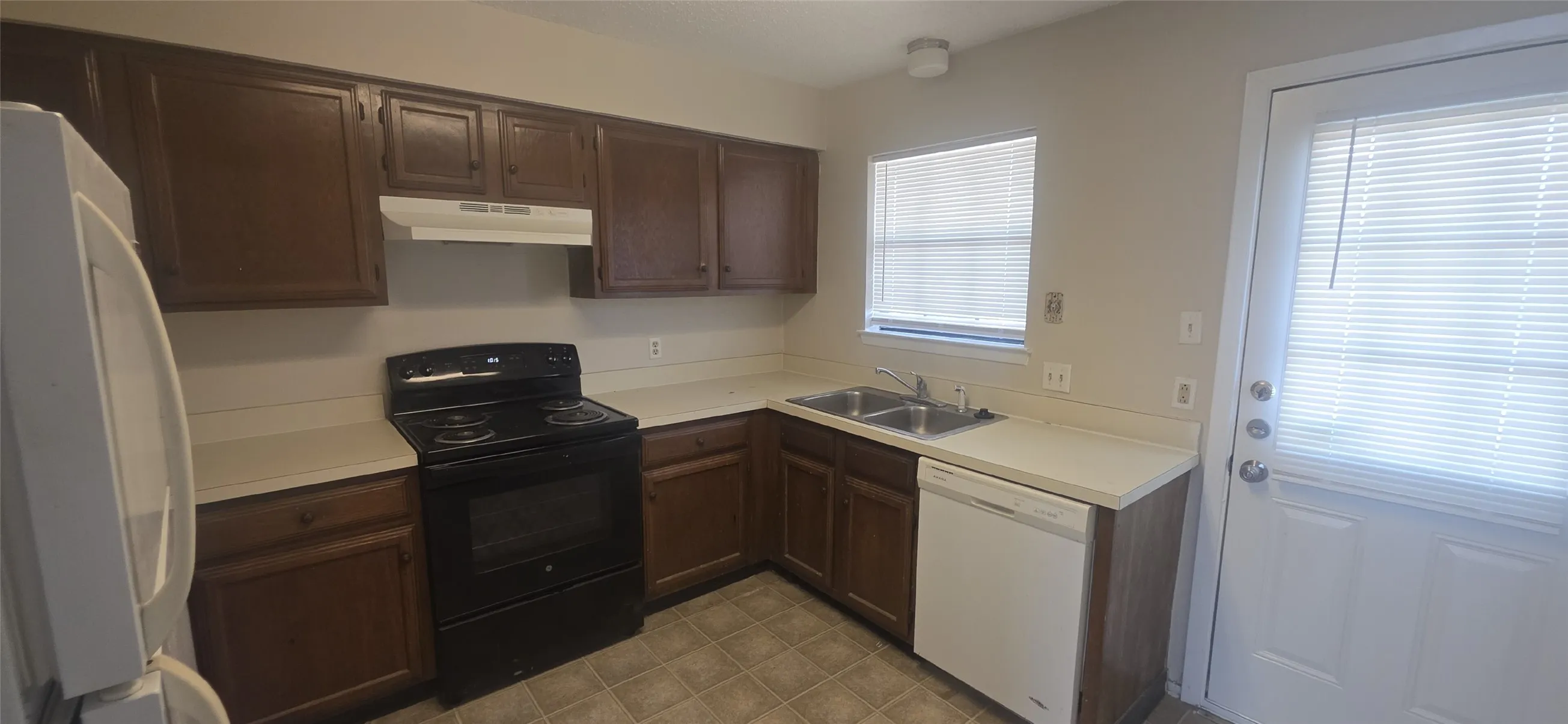 Wood-finish cabinetry, white countertops, built-in dishwasher, and a full-size range