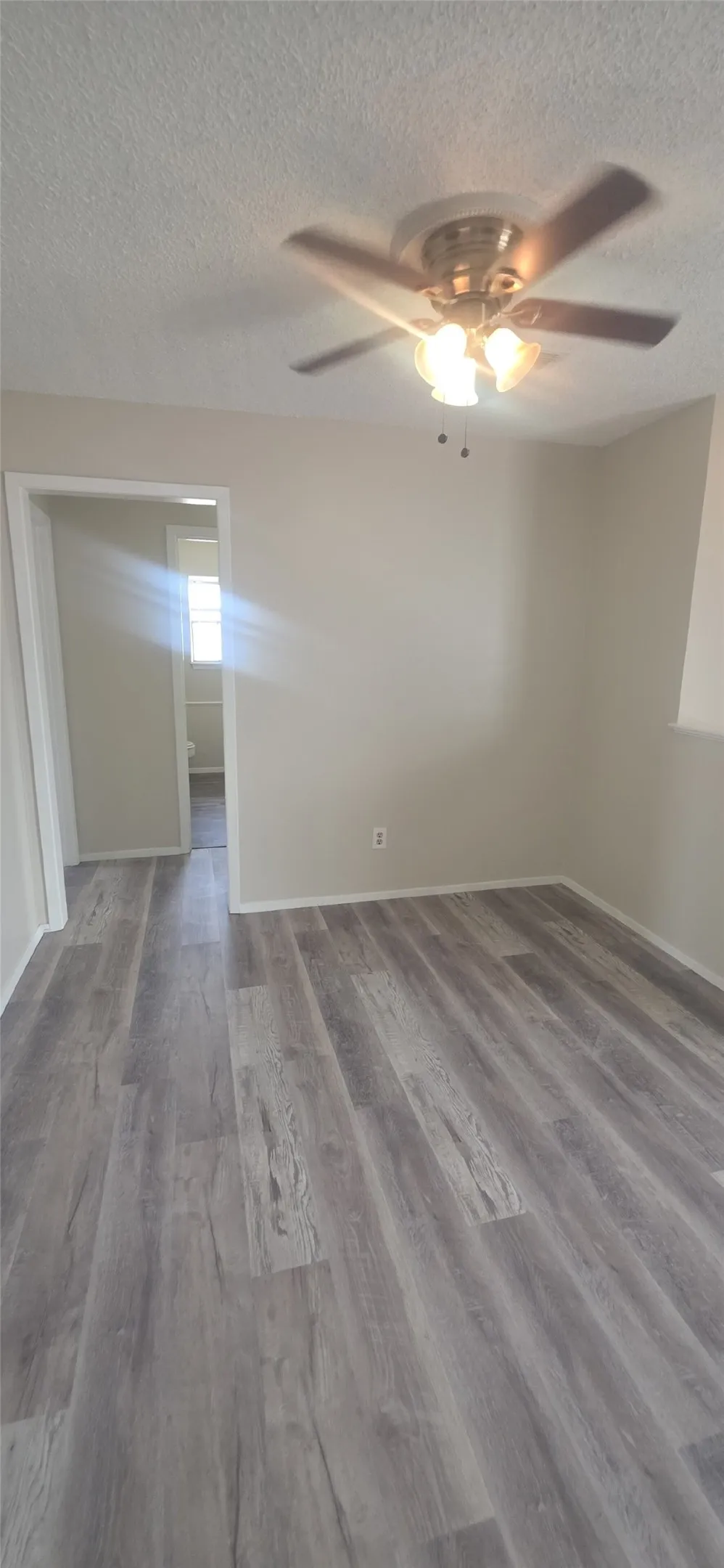 Wood-finish flooring, neutral wall tones, and an overhead ceiling fan with integrated lighting