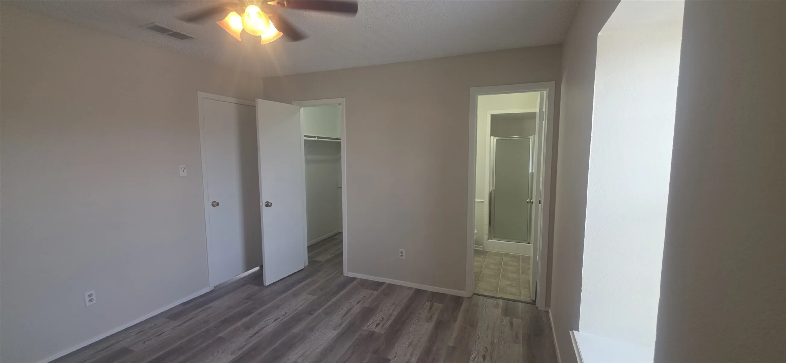 Wood-finish flooring, ceiling fan with integrated lighting, and multiple doors with round door handles
