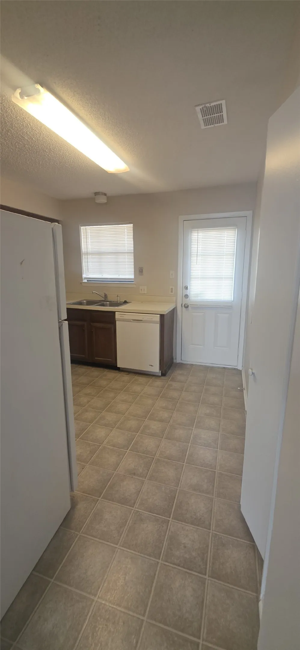 Kitchen featuring L-shaped counter space, a double basin sink, and a built-in dishwasher