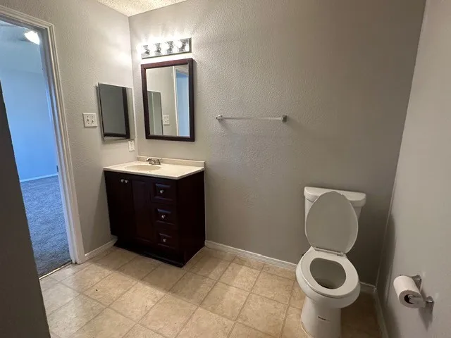 Bathroom featuring a dark wood finish vanity with integrated sink, coordinating wall-mounted mirror, and tile flooring