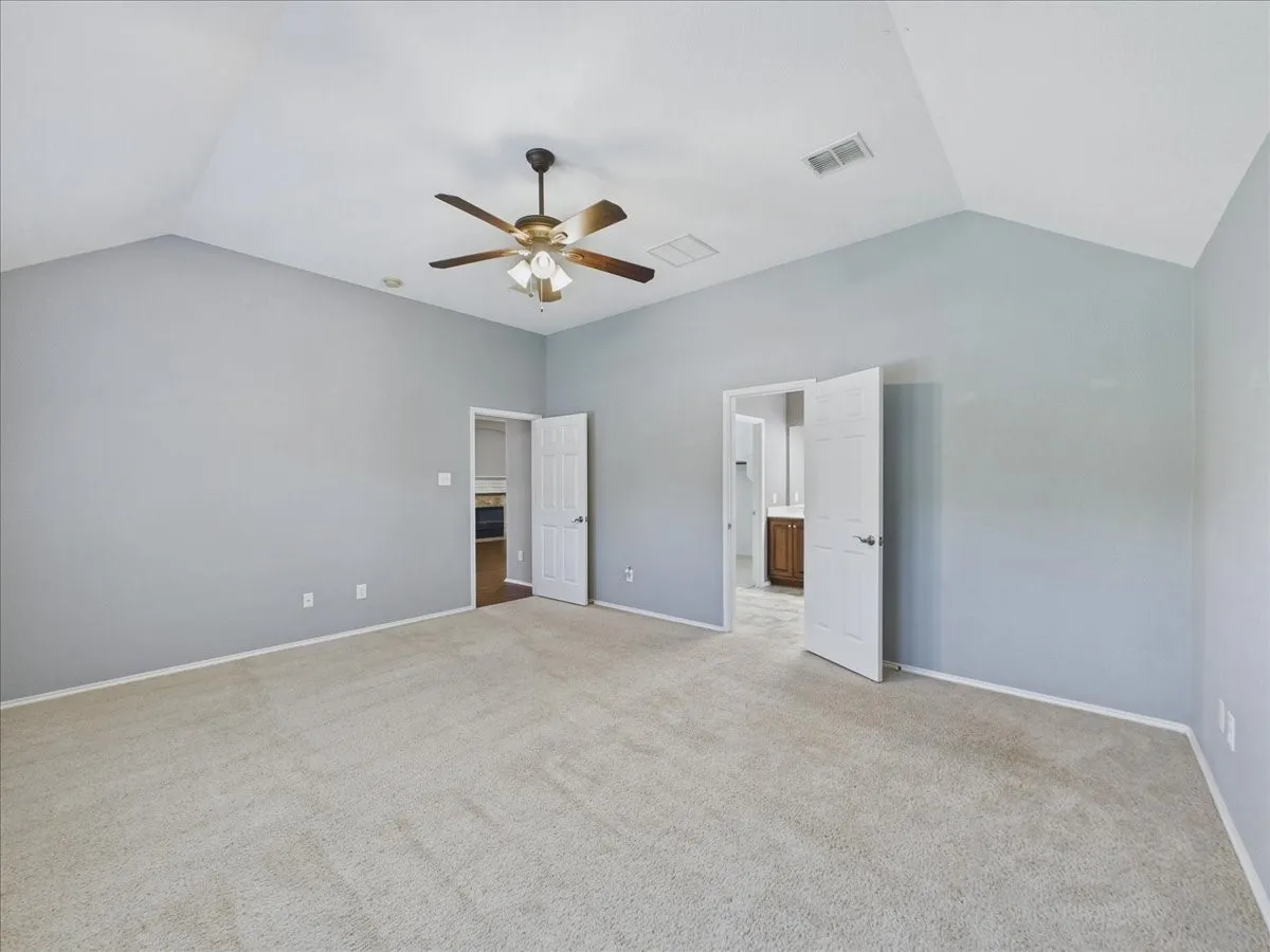 Vaulted ceiling, ceiling fan, neutral carpet, light gray wall color, and white trim