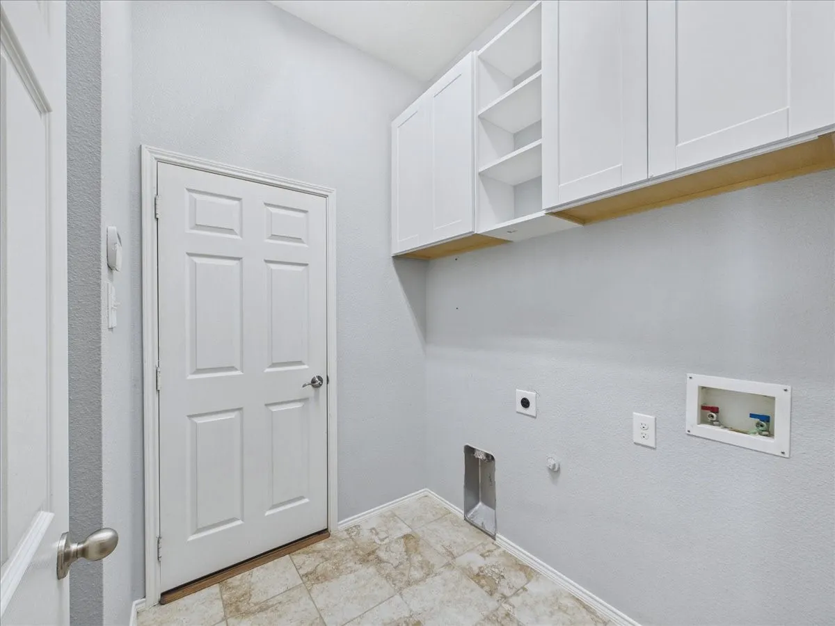 White shaker-style cabinetry with open shelving, tile flooring, and utility hookups
