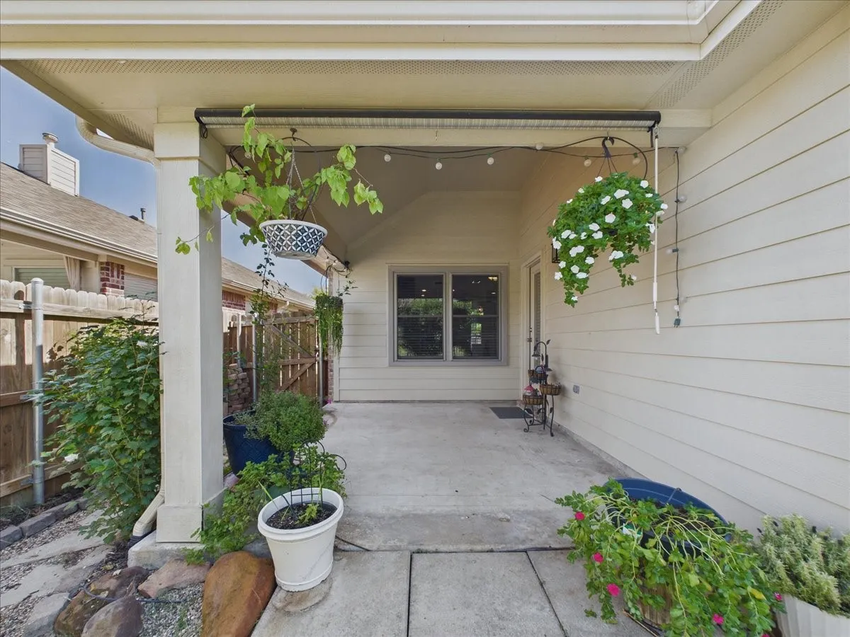 Covered patio featuring concrete flooring, a single window, and a door with an exterior light fixture