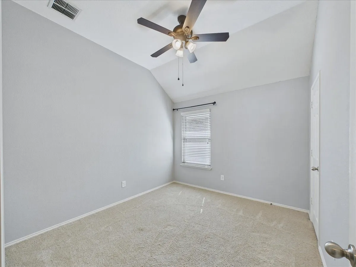 Vaulted ceiling with ceiling fan, carpeting, window with blinds, and white door