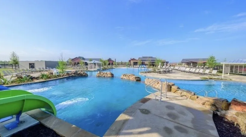Expansive aquatic center featuring multiple pools, a water slide, and rock accents
