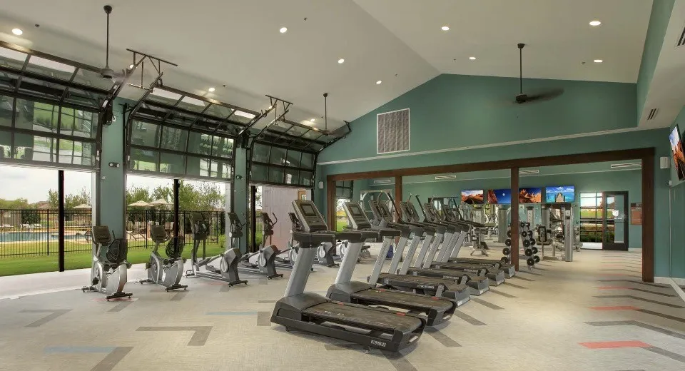 Vaulted ceiling fitness center with multiple treadmills, ellipticals, and stationary bikes