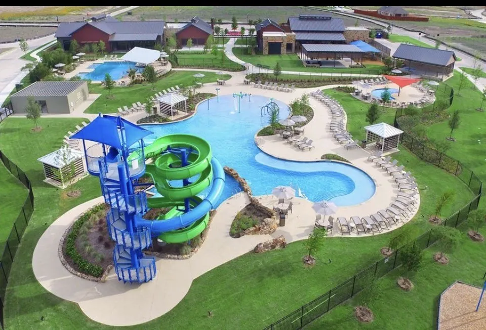 Resort-style aquatic amenity featuring multiple pools, water slides, and extensive decking with lounge seating