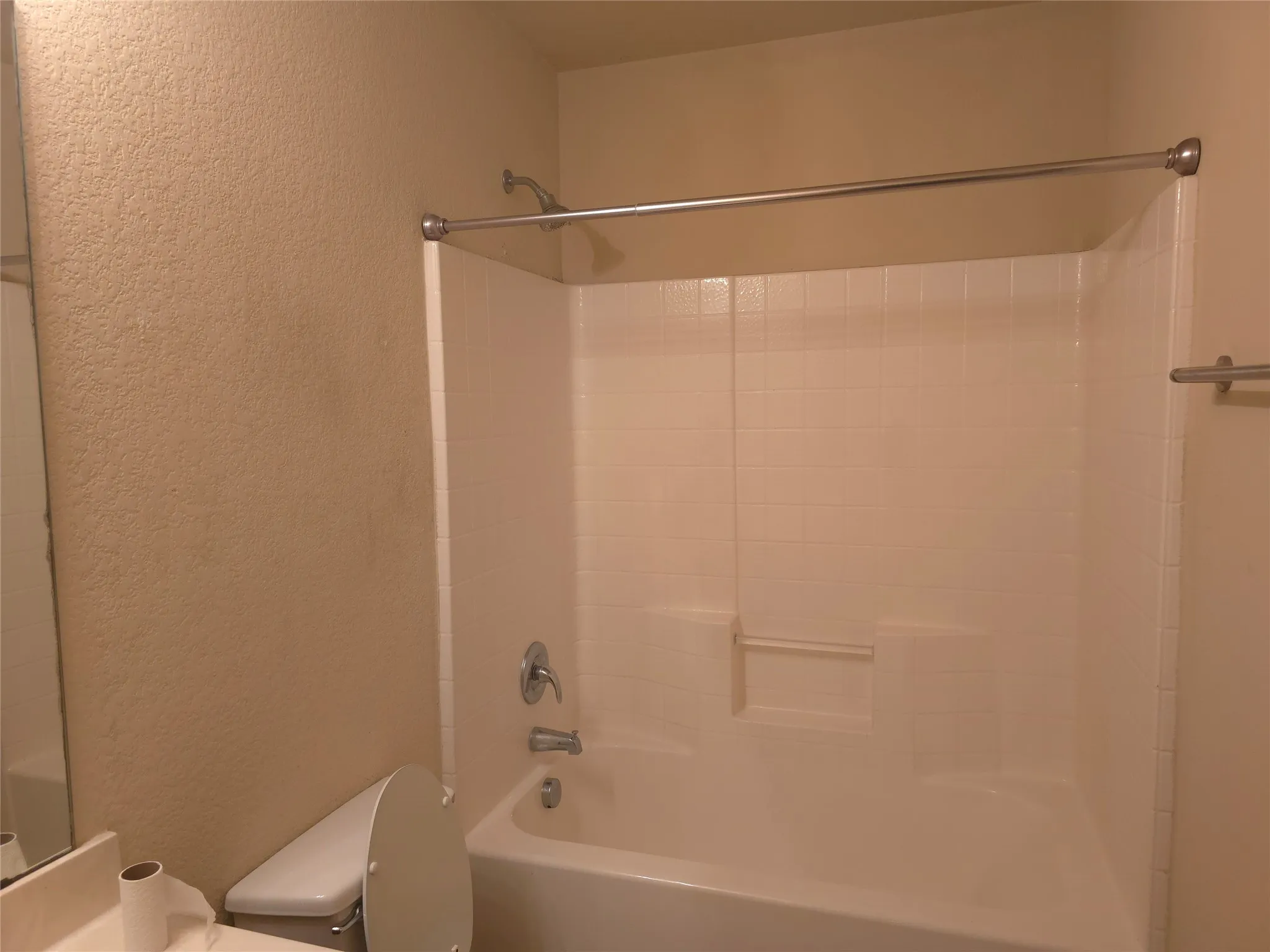 Bathtub and shower combination with a curved shower curtain rod, a chrome showerhead, and a matching chrome faucet