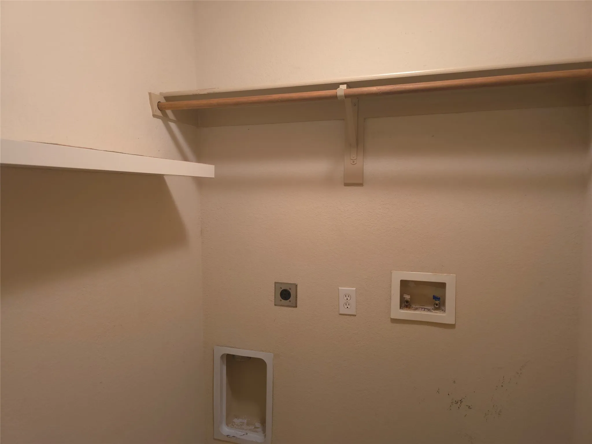 Laundry area featuring a built-in shelf and clothing rod