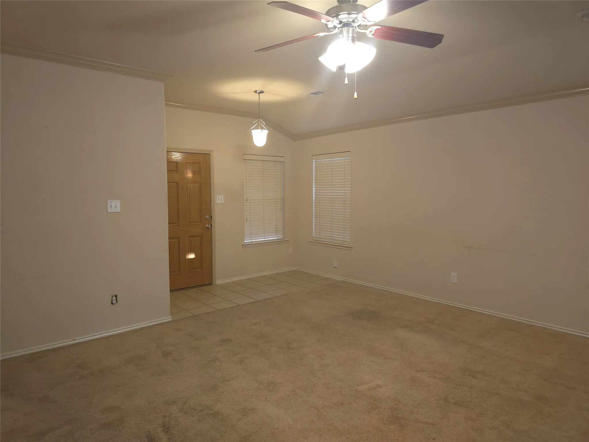 Spacious interior with vaulted ceilings, a ceiling fan, and crown molding
