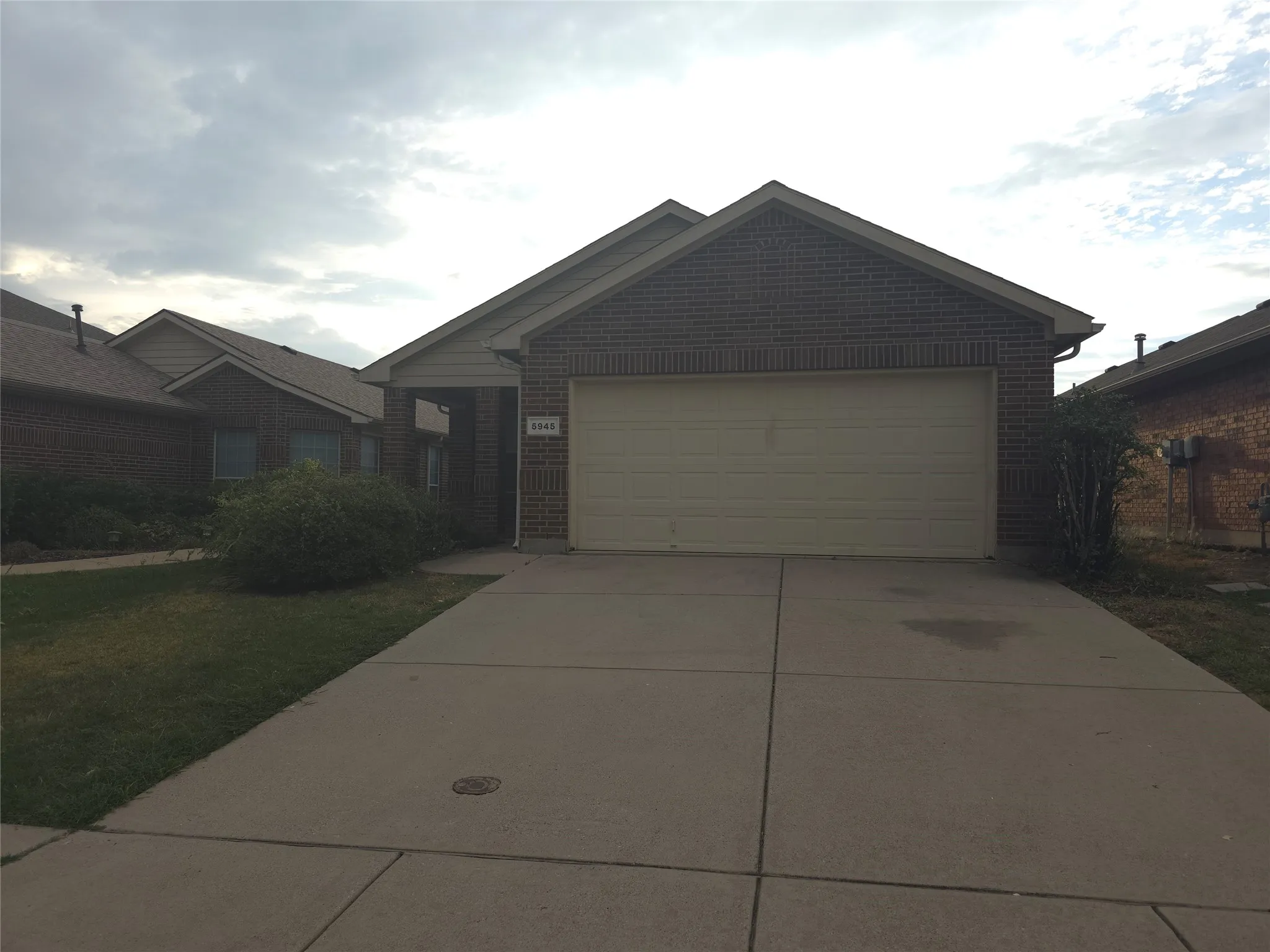 Brick facade with a large attached garage, gabled roofline, and concrete driveway