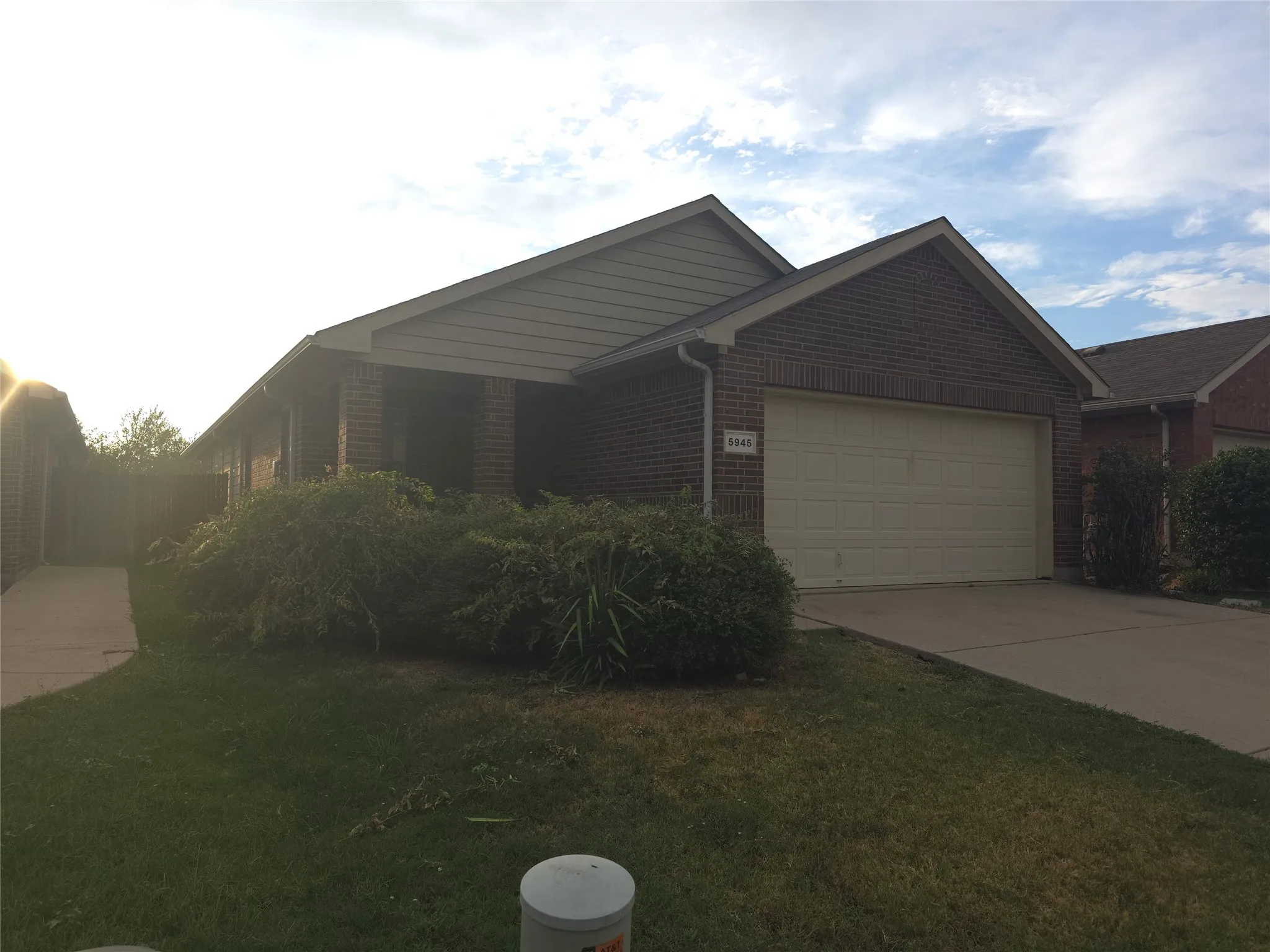 Brick facade with gabled roofline, attached garage, and concrete driveway