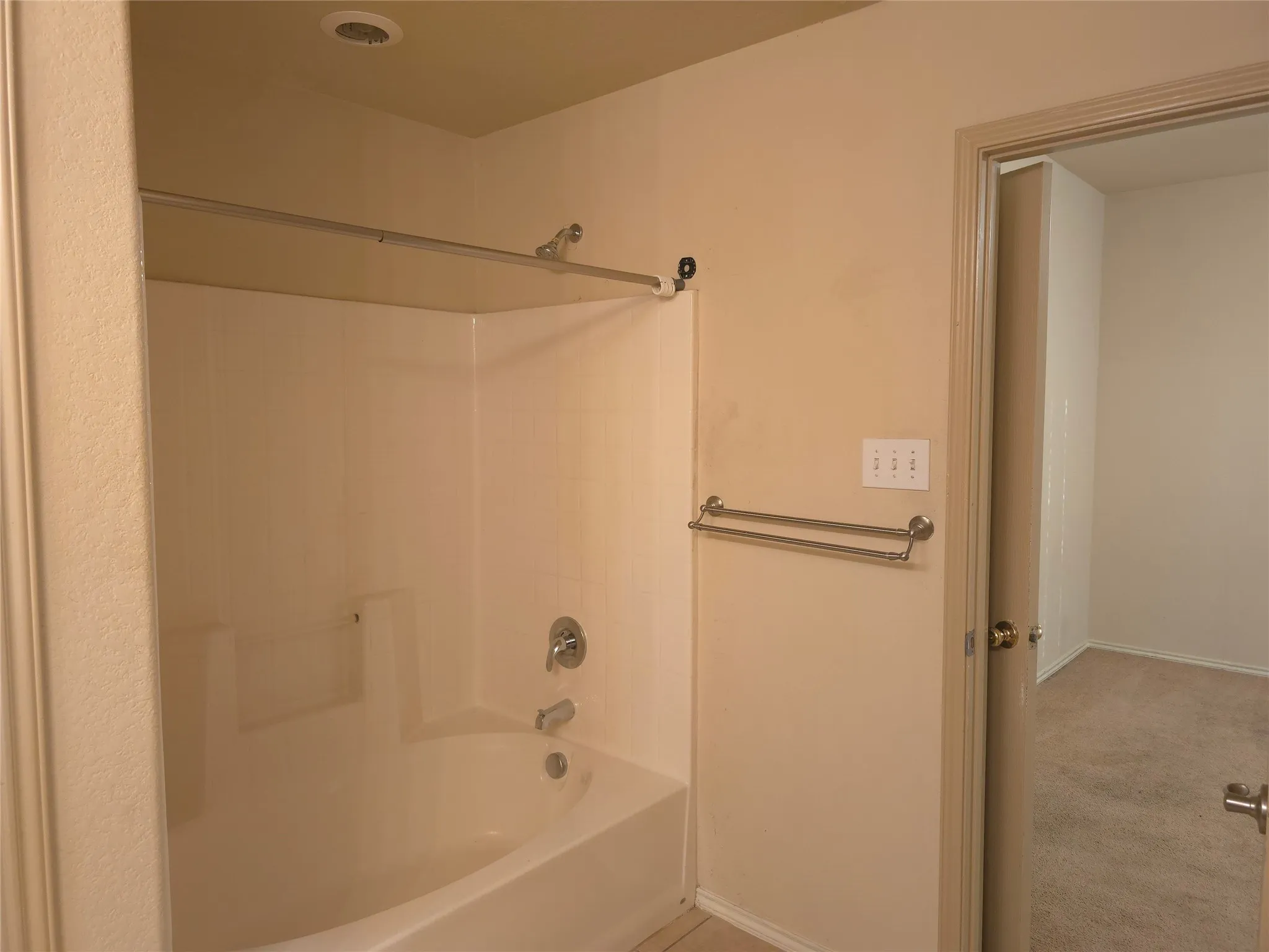 White bathtub and shower combination with chrome fixtures and integrated shelving