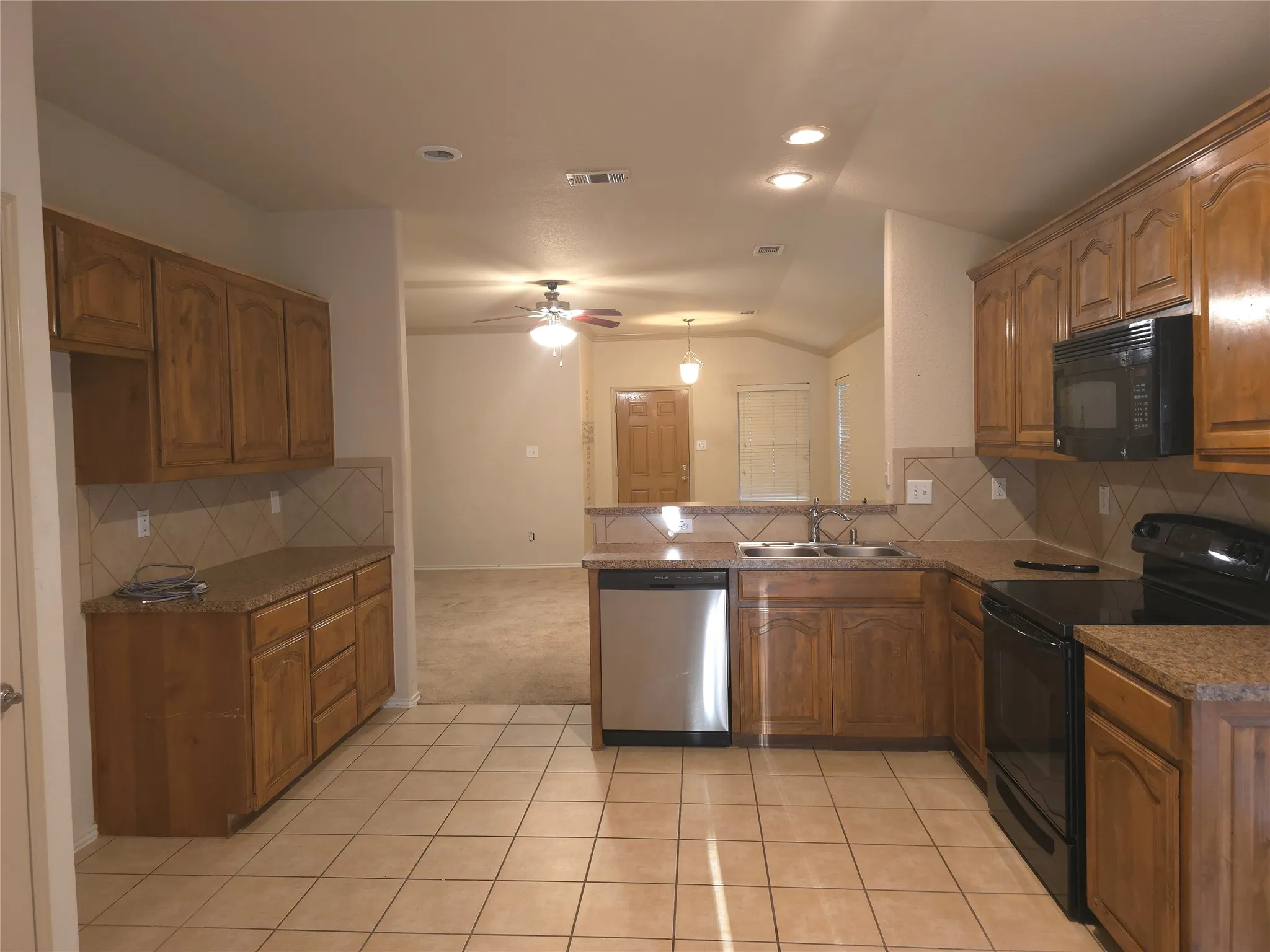 Kitchen featuring tile flooring, wood cabinetry, granite countertops, and a tile backsplash