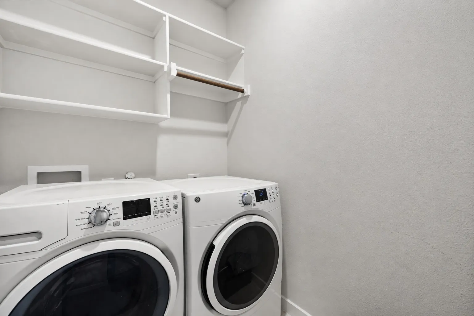 Laundry area with built-in shelving and a clothing rod