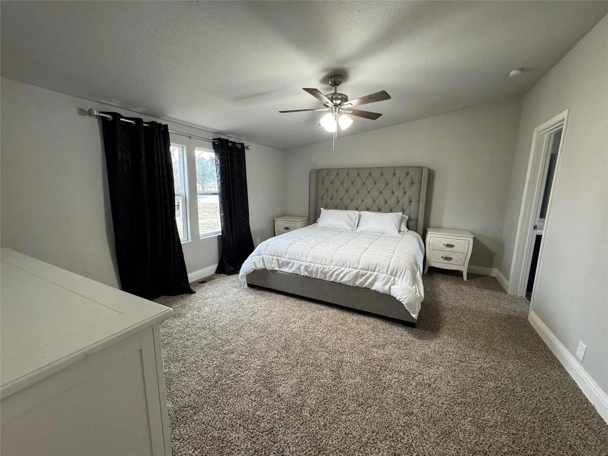 Master bedroom with king size bed, two nightstands, long dresser and lots of space left.