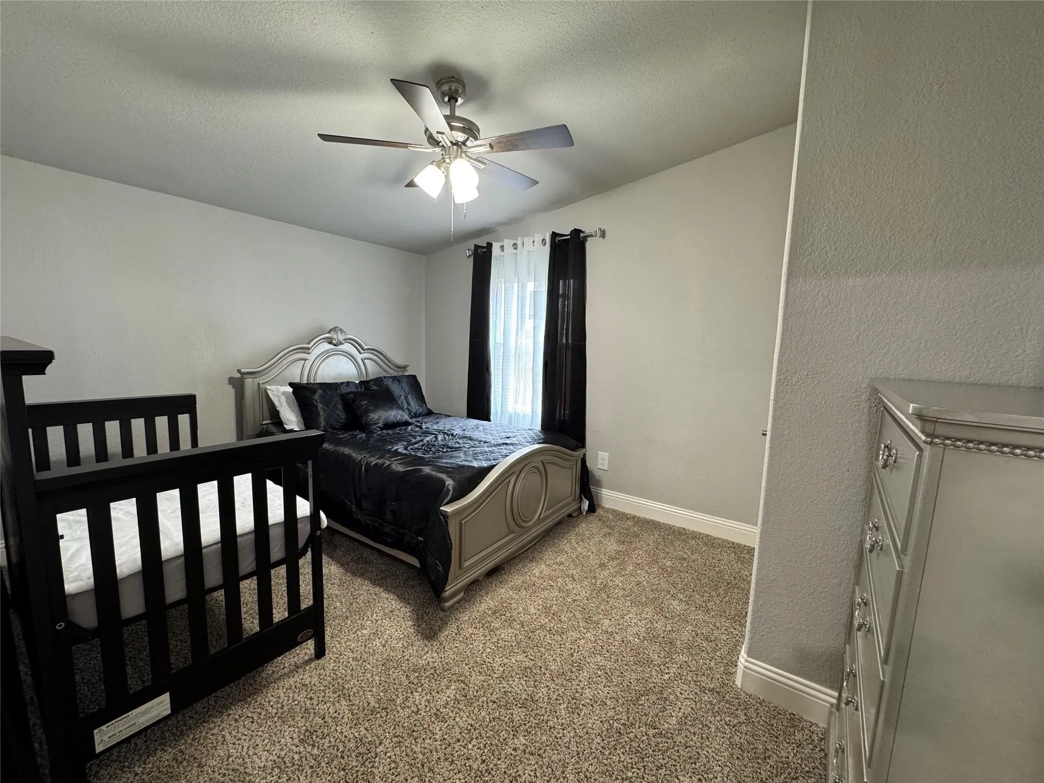 Bedroom three with a queen size bed, baby crib and dresser.