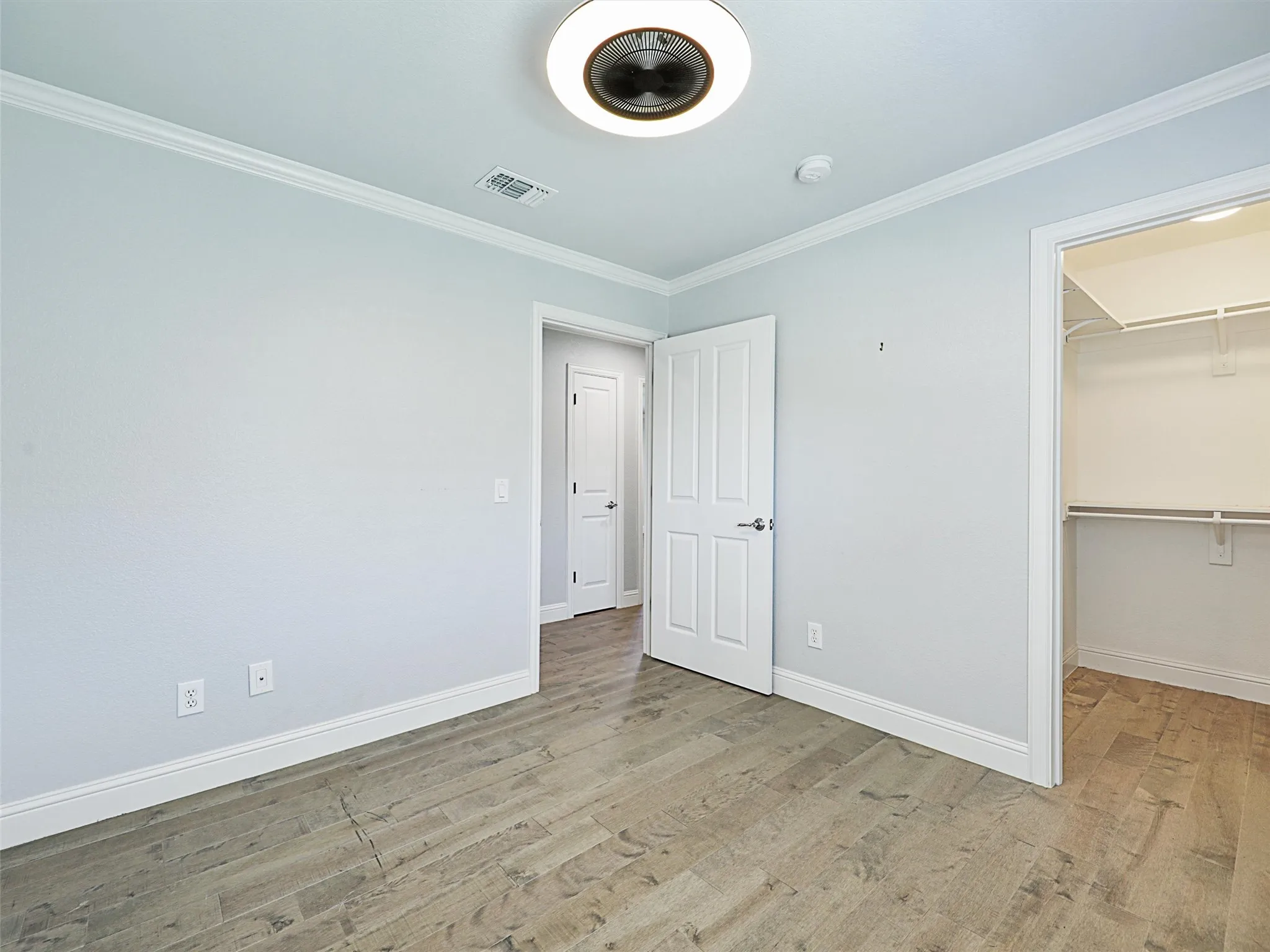Second bedroom featuring crown molding, a walk in closet, and LVP