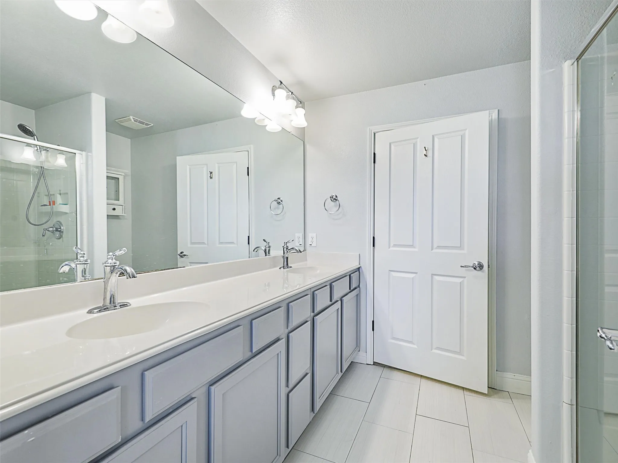 Bathroom with tile floors, walk in shower, oversized vanity, and dual sinks