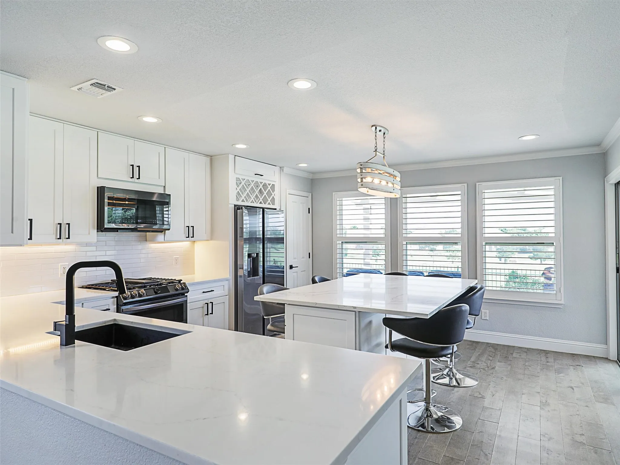 Kitchen with a kitchen island, hanging light fixtures, tasteful backsplash, black appliances. Adjustable Bar Height Stools are included!