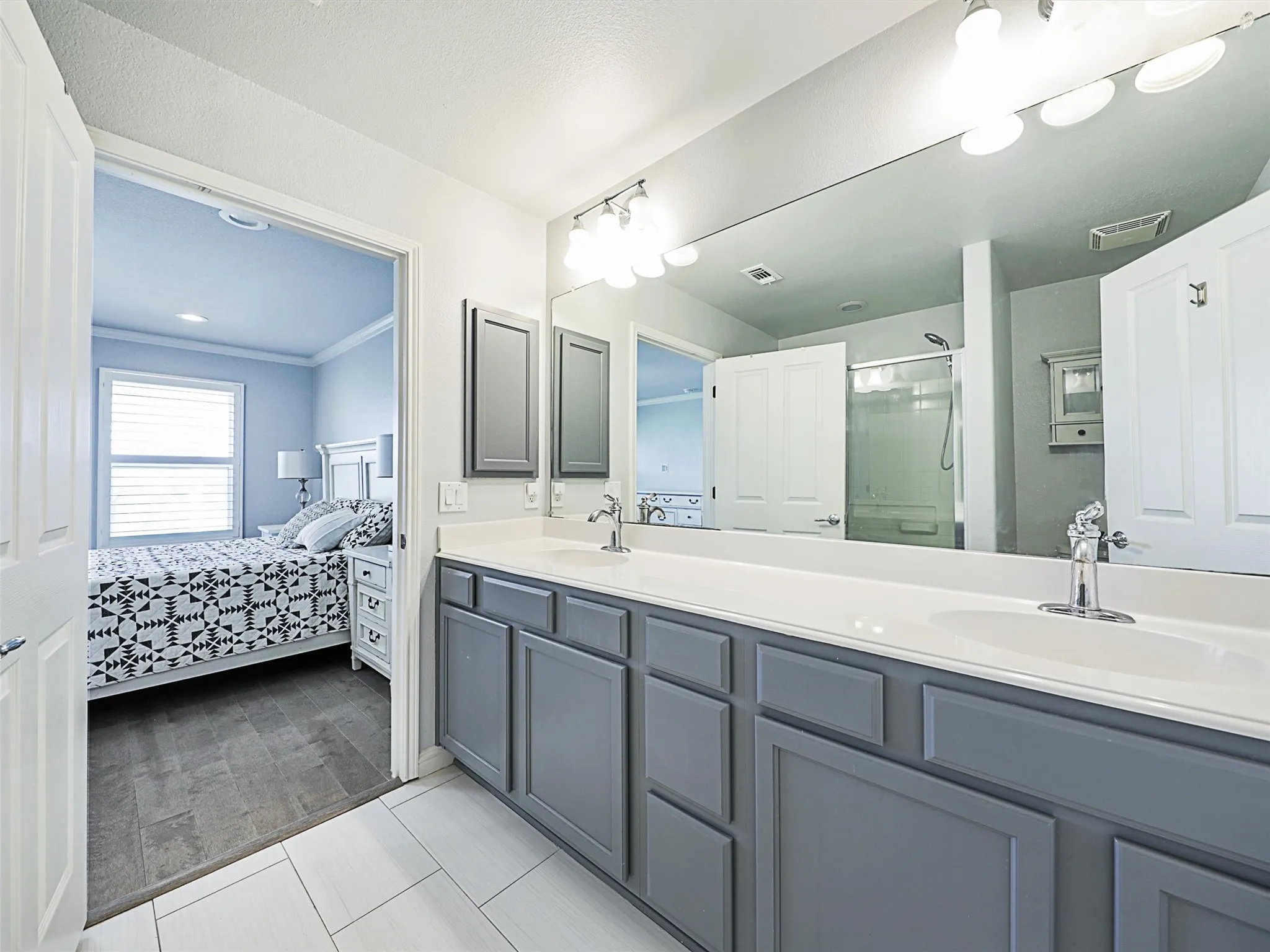 Bathroom with ornamental molding, an enclosed shower, and double sink vanity