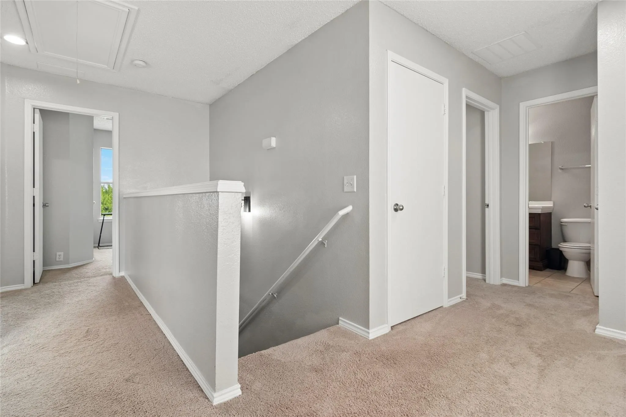 Carpeted hallway with light gray walls, white trim, and white doors