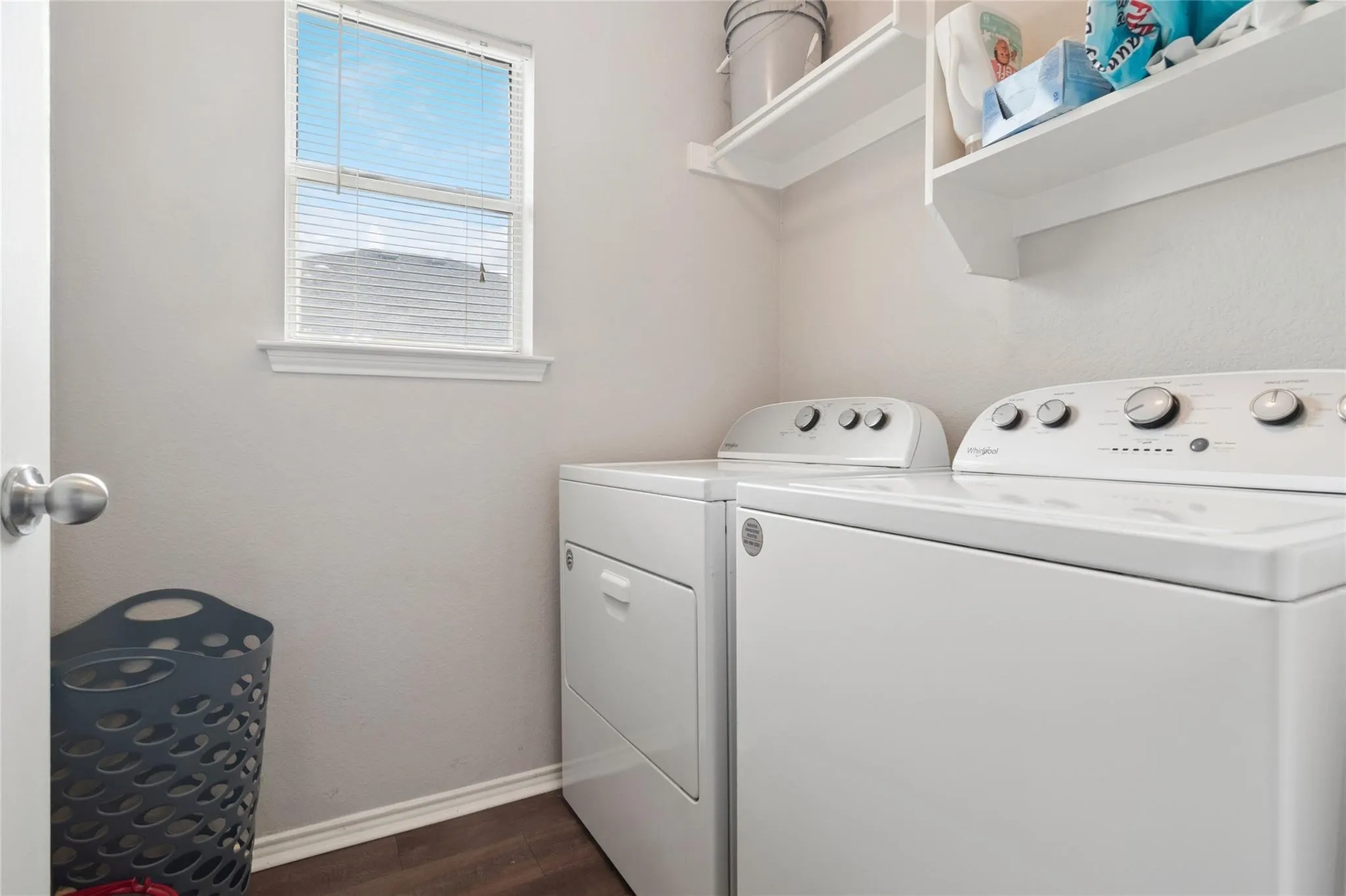Built-in overhead shelving, a single window with blinds, and wood-finish flooring