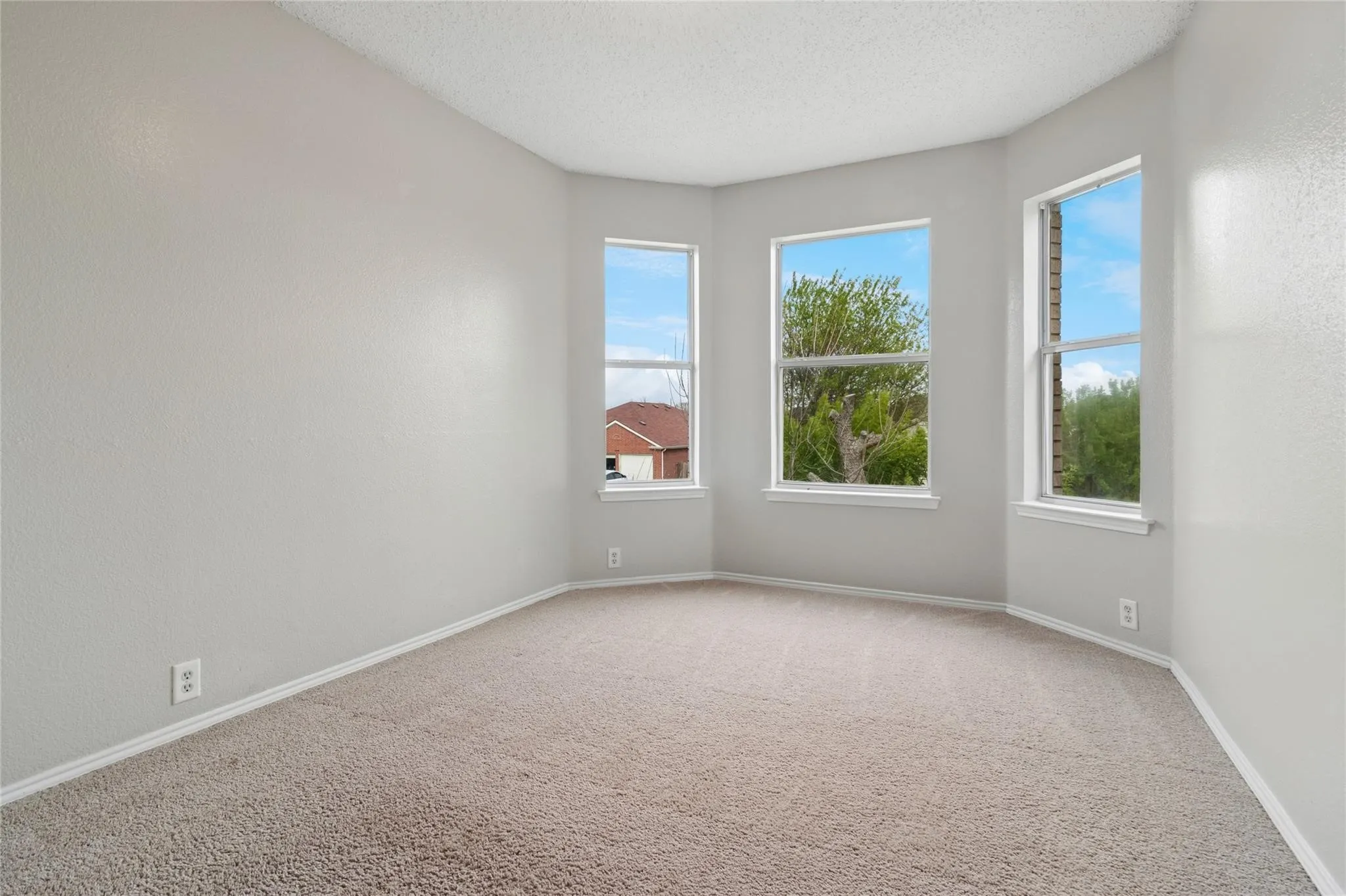 Bay window with three windows, neutral-toned walls, and plush carpeting