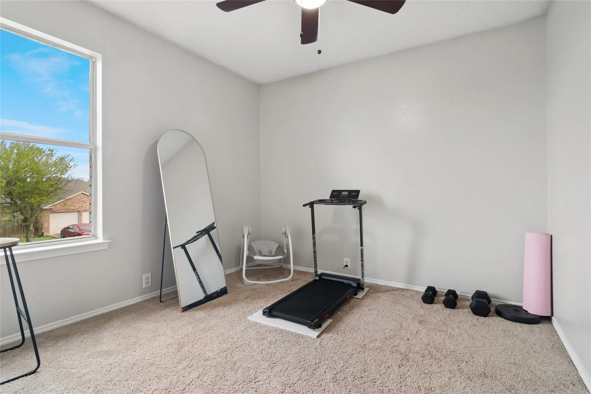 Neutral wall paint, carpet flooring, a single window, and a ceiling fan
