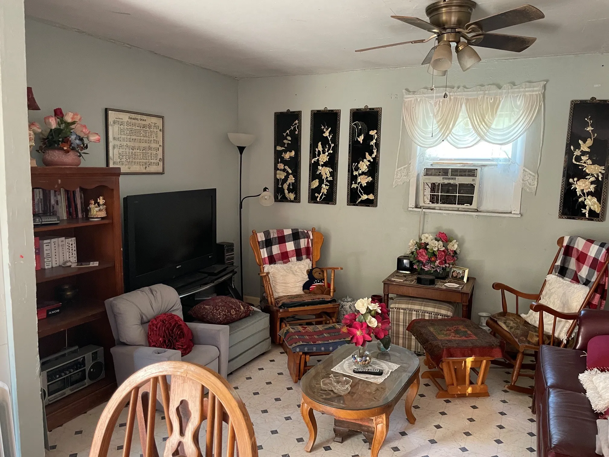 Ceiling fan with integrated lighting, window-mounted air conditioning unit, built-in shelving, and wood-finish flooring