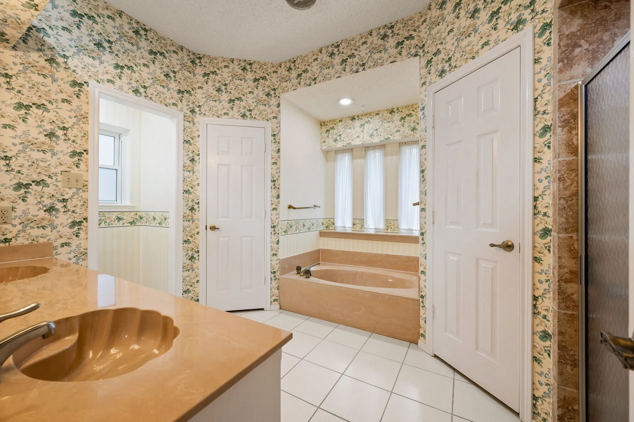 Bathroom featuring a built-in soaking tub, a dual-sink vanity with an integrated shell-style basin, ceramic tile flooring, and a walk-in shower enclosure