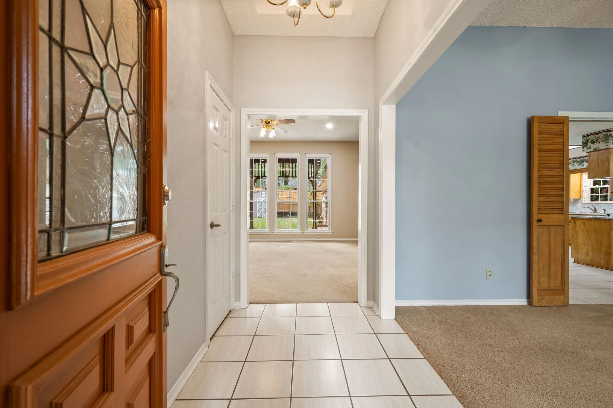Entry featuring a wood-framed door with decorative glass paneling, tile flooring, recessed ceiling lighting, and a louvered closet door