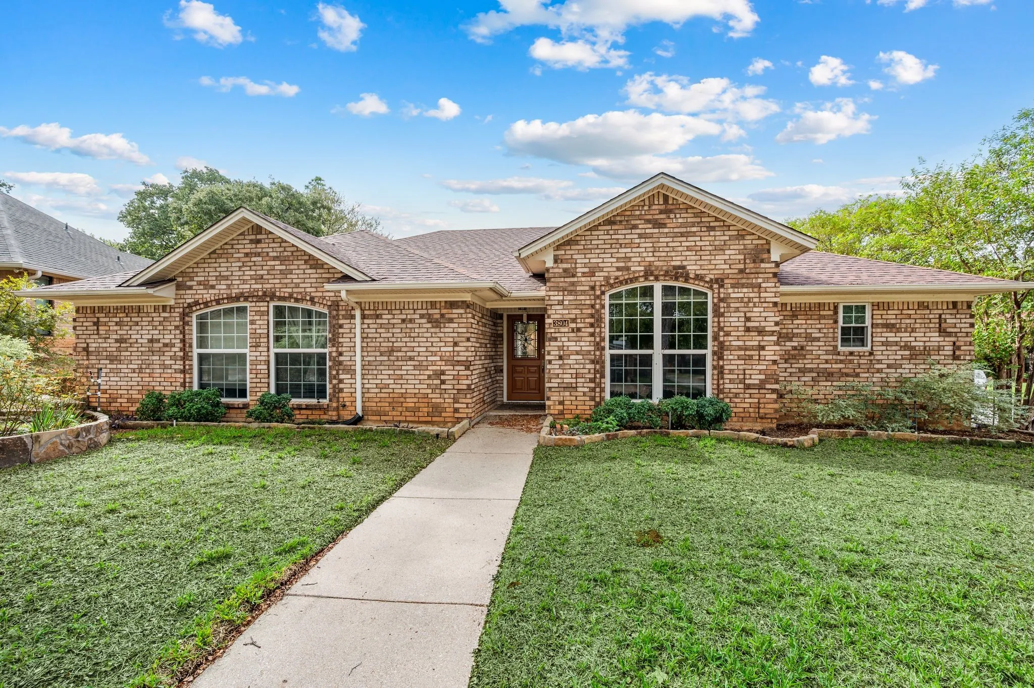Single-story brick exterior featuring a multi-gabled roofline, arched window detailing, and a concrete walkway