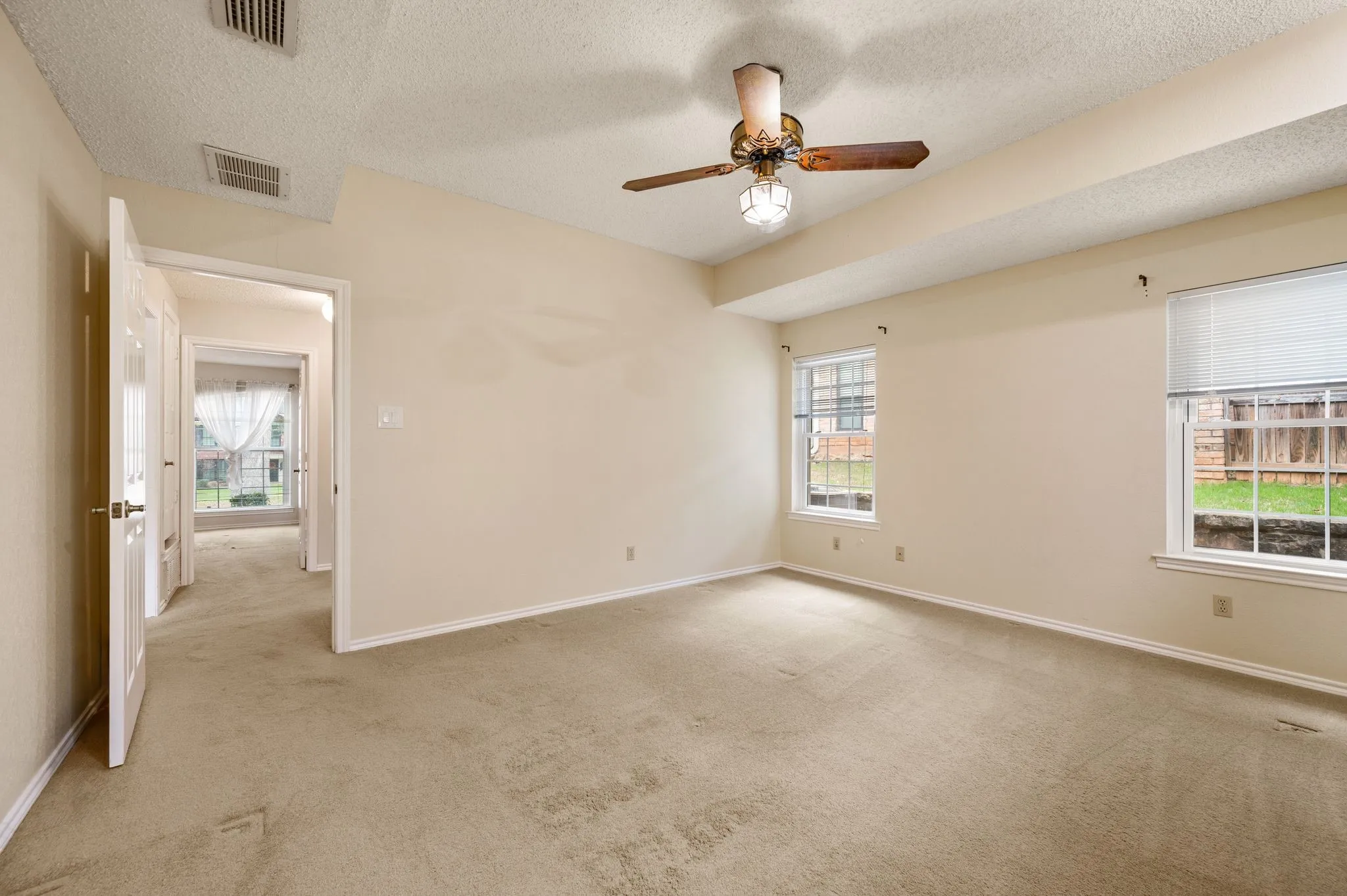 Neutral-toned wall-to-wall carpeting, ceiling fan with integrated lighting, and multiple windows with white blinds