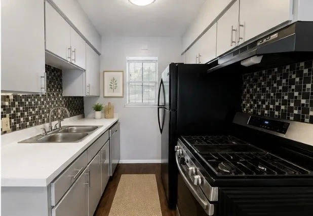 Galley kitchen featuring white upper cabinetry, grey lower cabinetry, a mosaic tile backsplash, and wood-finish flooring
