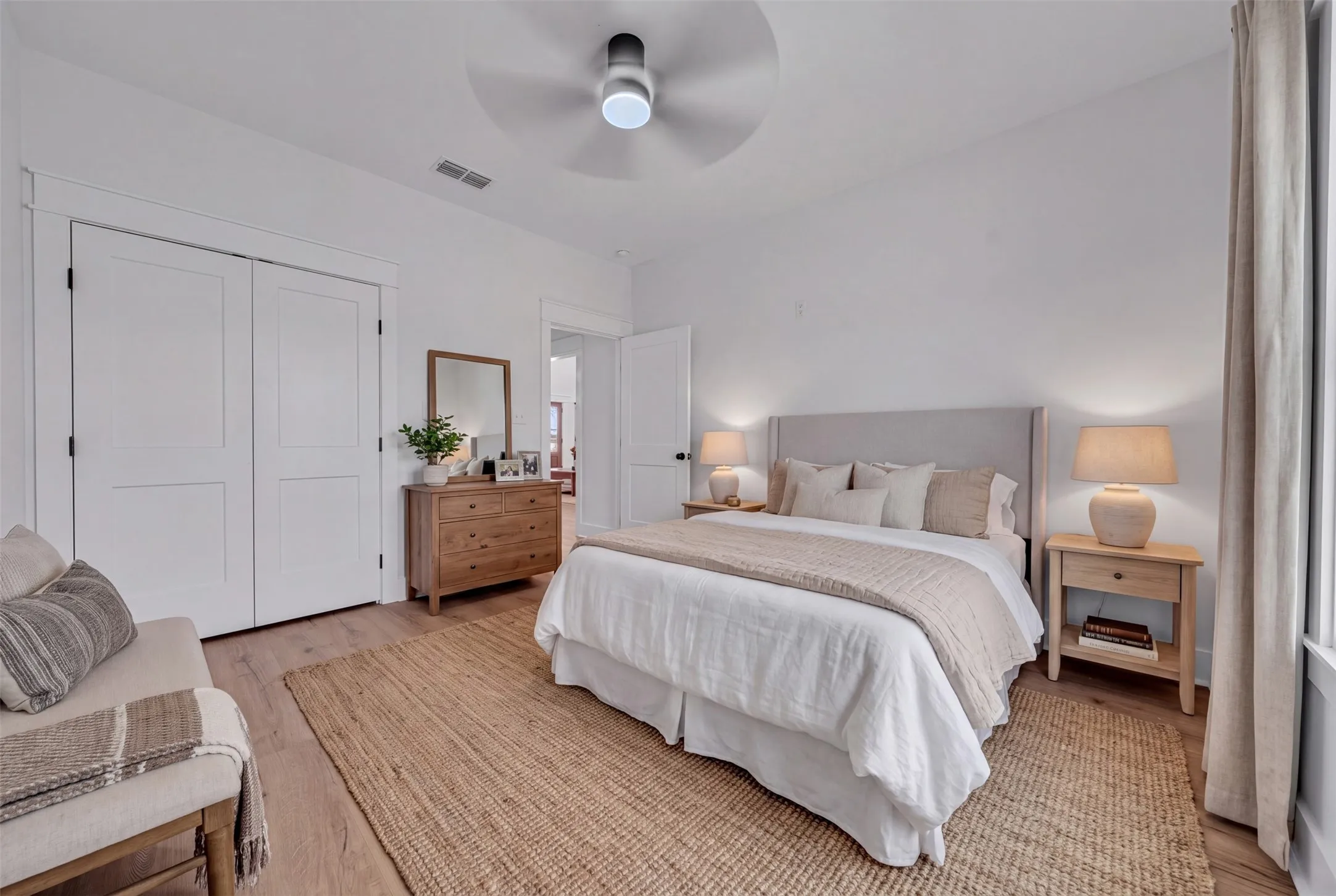 Wood-finish flooring throughout, bright white walls, and a contemporary ceiling fan