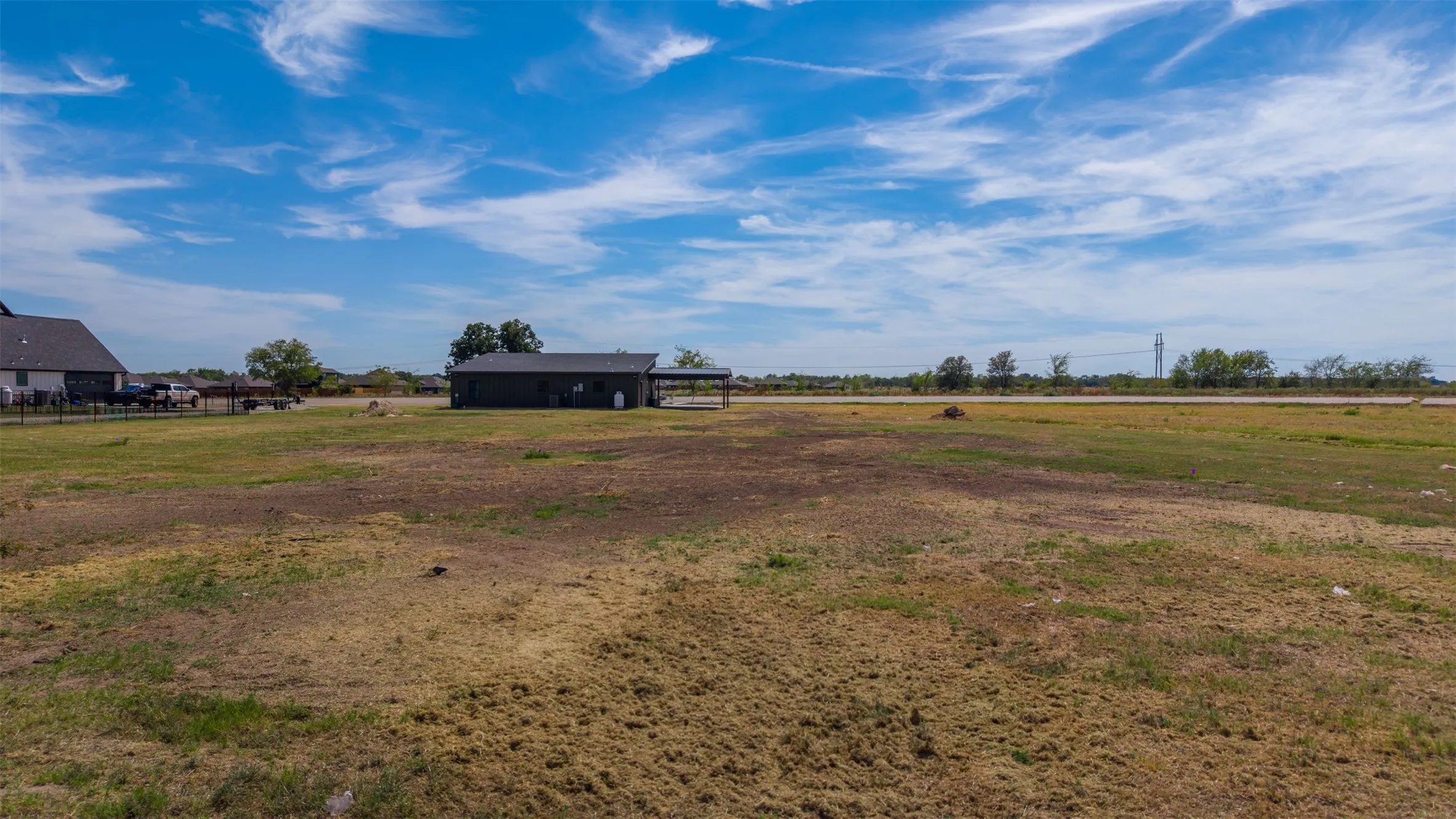Expansive open land with a distant outbuilding and clear blue skies