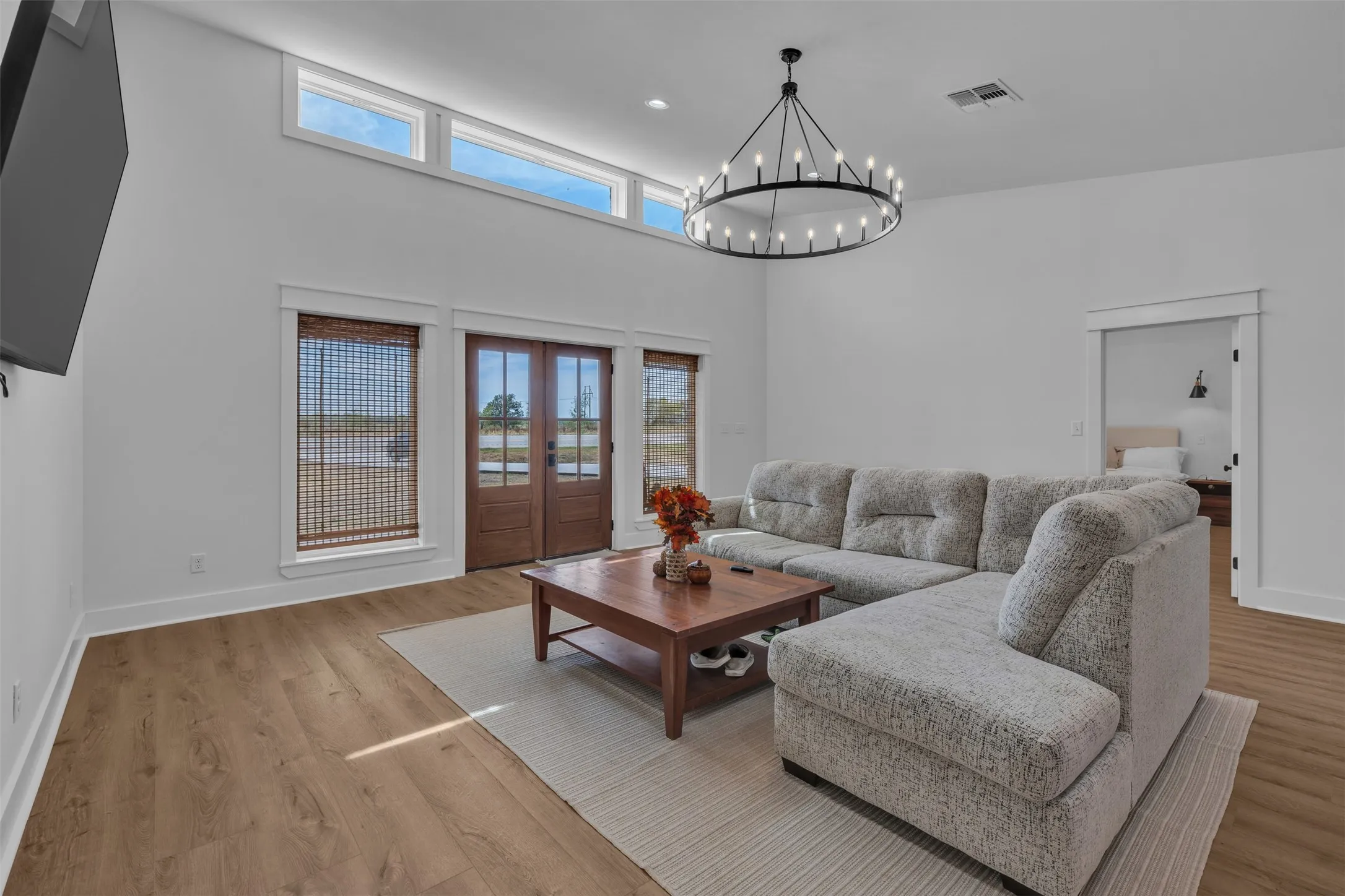 Vaulted ceilings with transom windows, wood-finish flooring, and a large circular chandelier