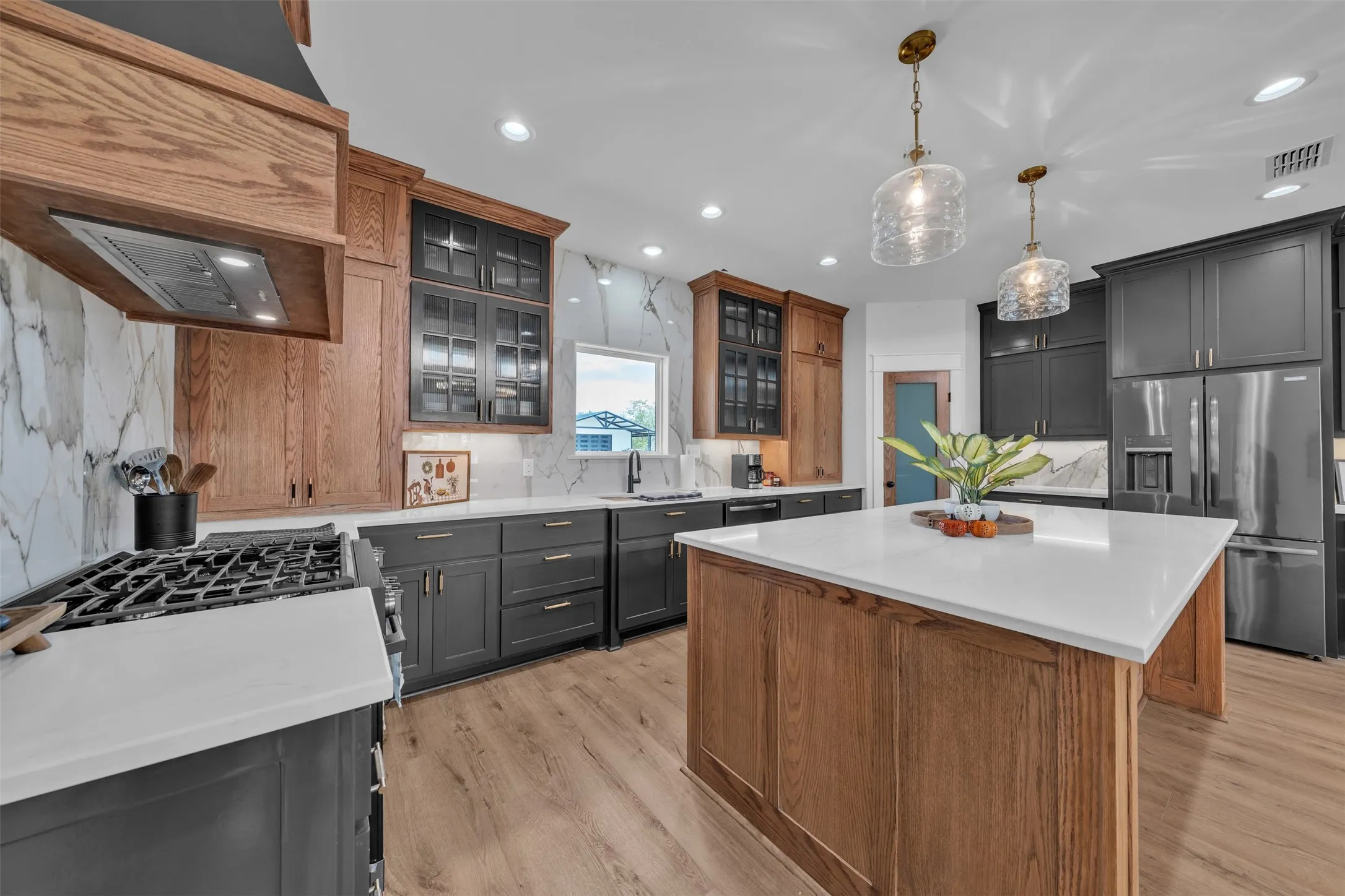 Gourmet kitchen featuring a central island, stainless steel appliances, wood-finish flooring, recessed lighting, and quartz countertops