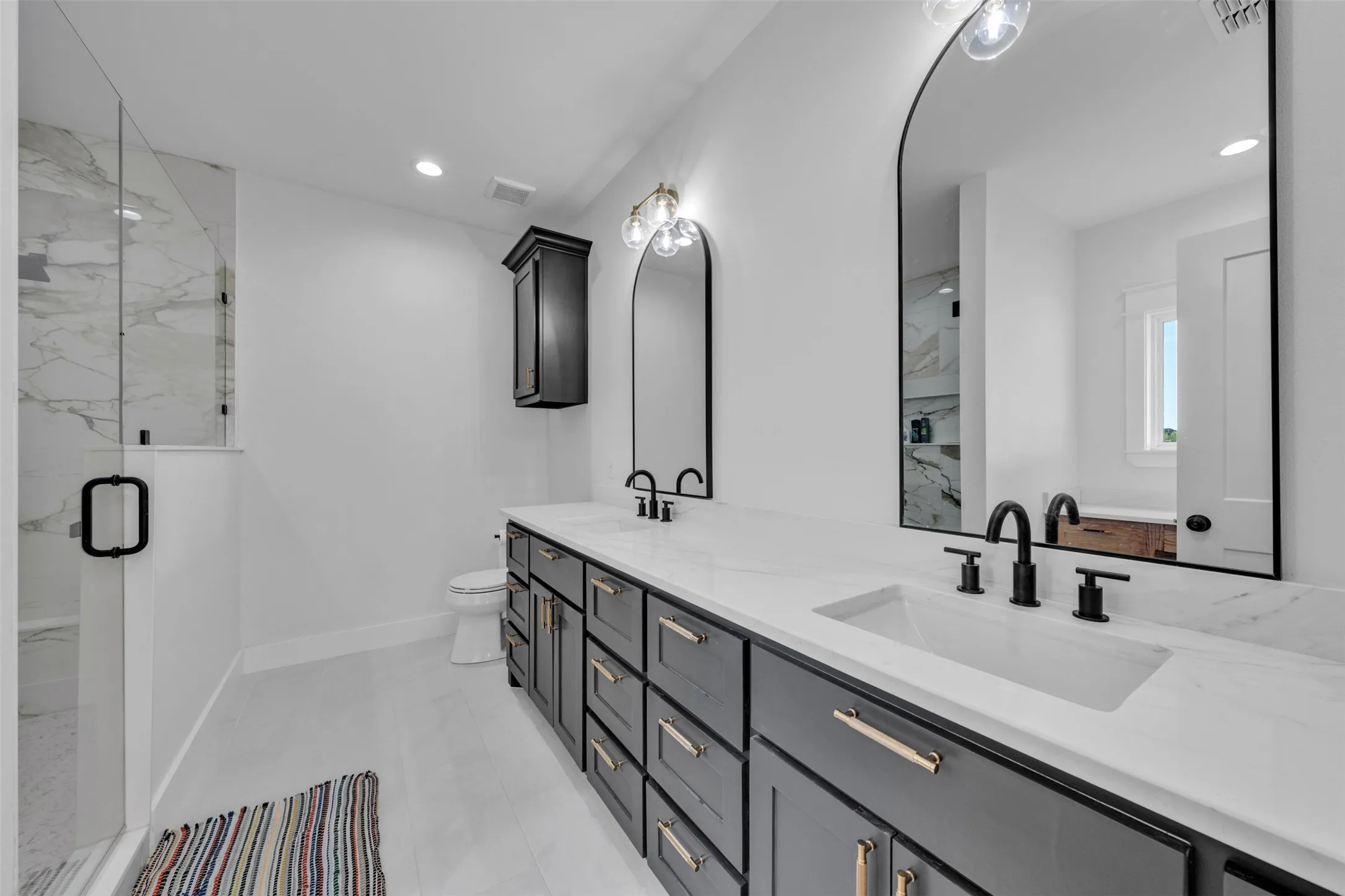 Dual-sink vanity with matte black fixtures, arched mirrors, and gold-tone hardware