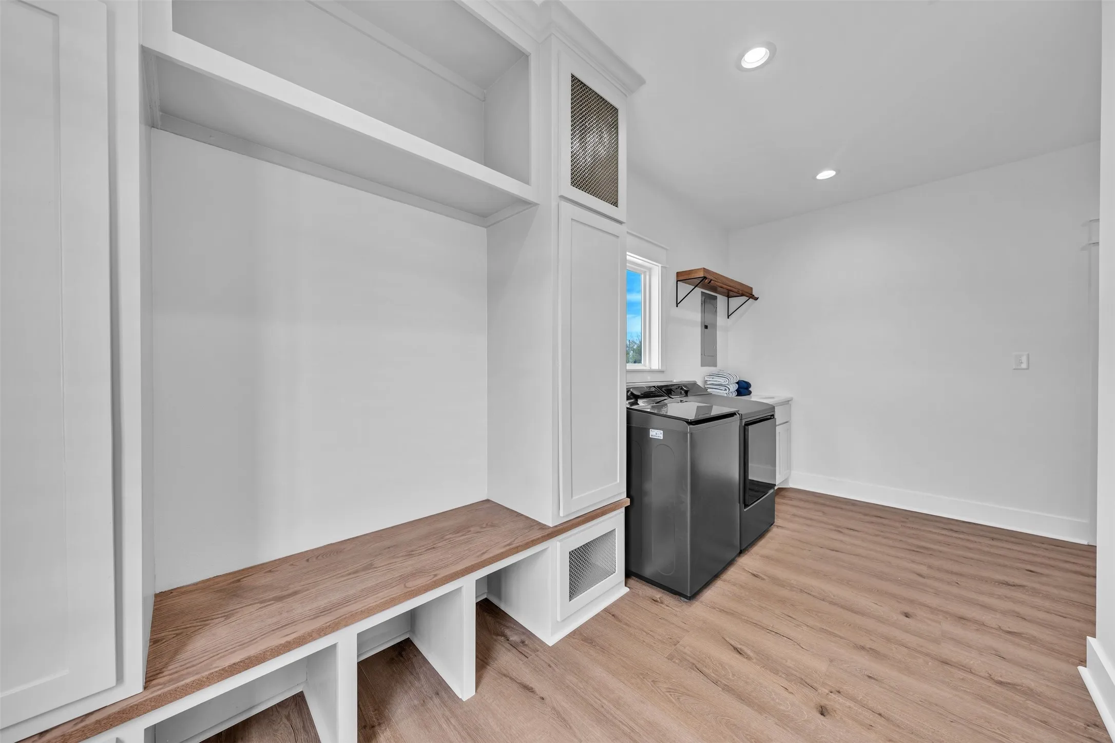 Built-in storage cabinetry with open shelving, wood-finish bench seating, recessed lighting, and wood-finish flooring