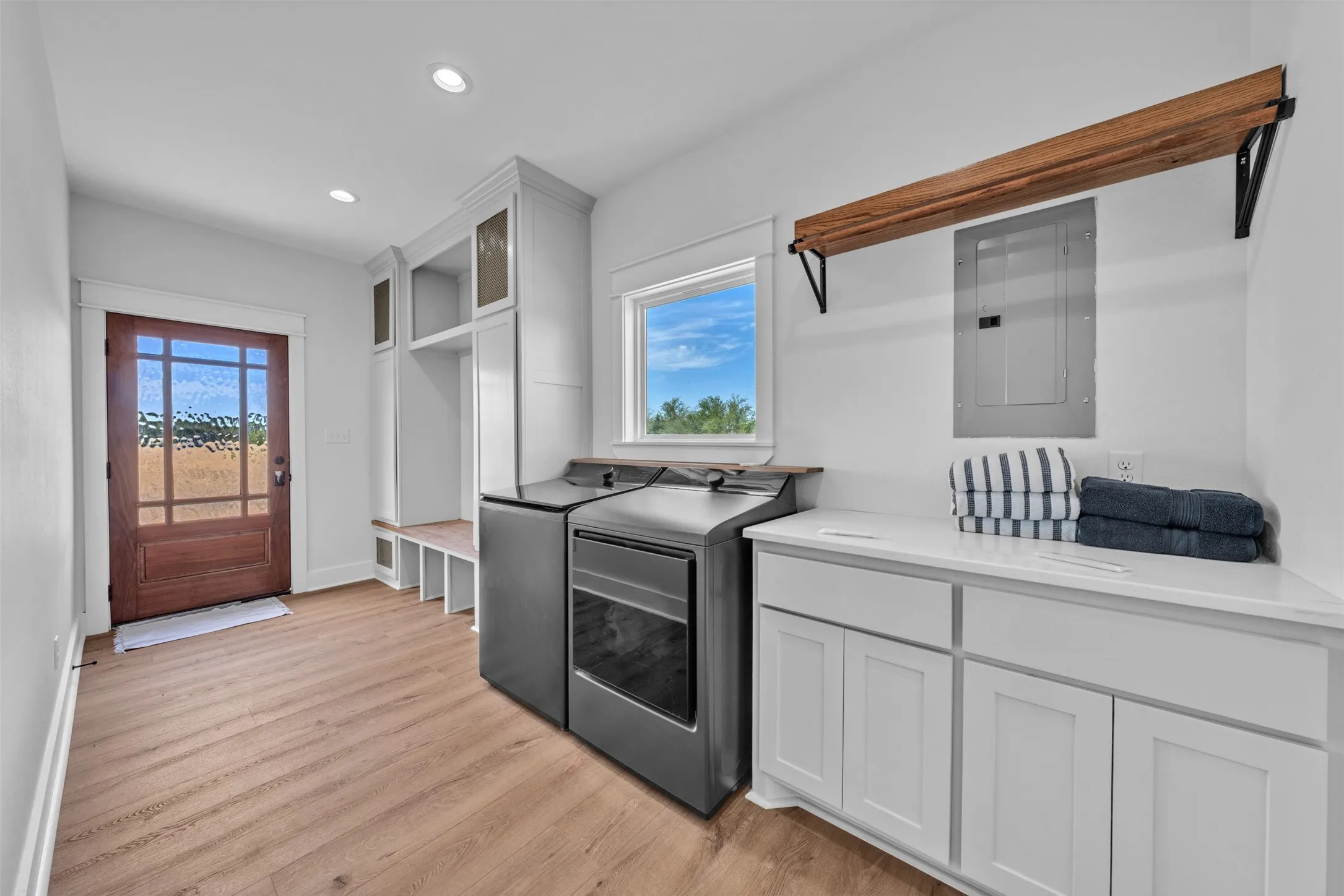 Wood-finish flooring, built-in cabinetry with bench seating, white countertops, window with natural light, and a wood-beam shelf