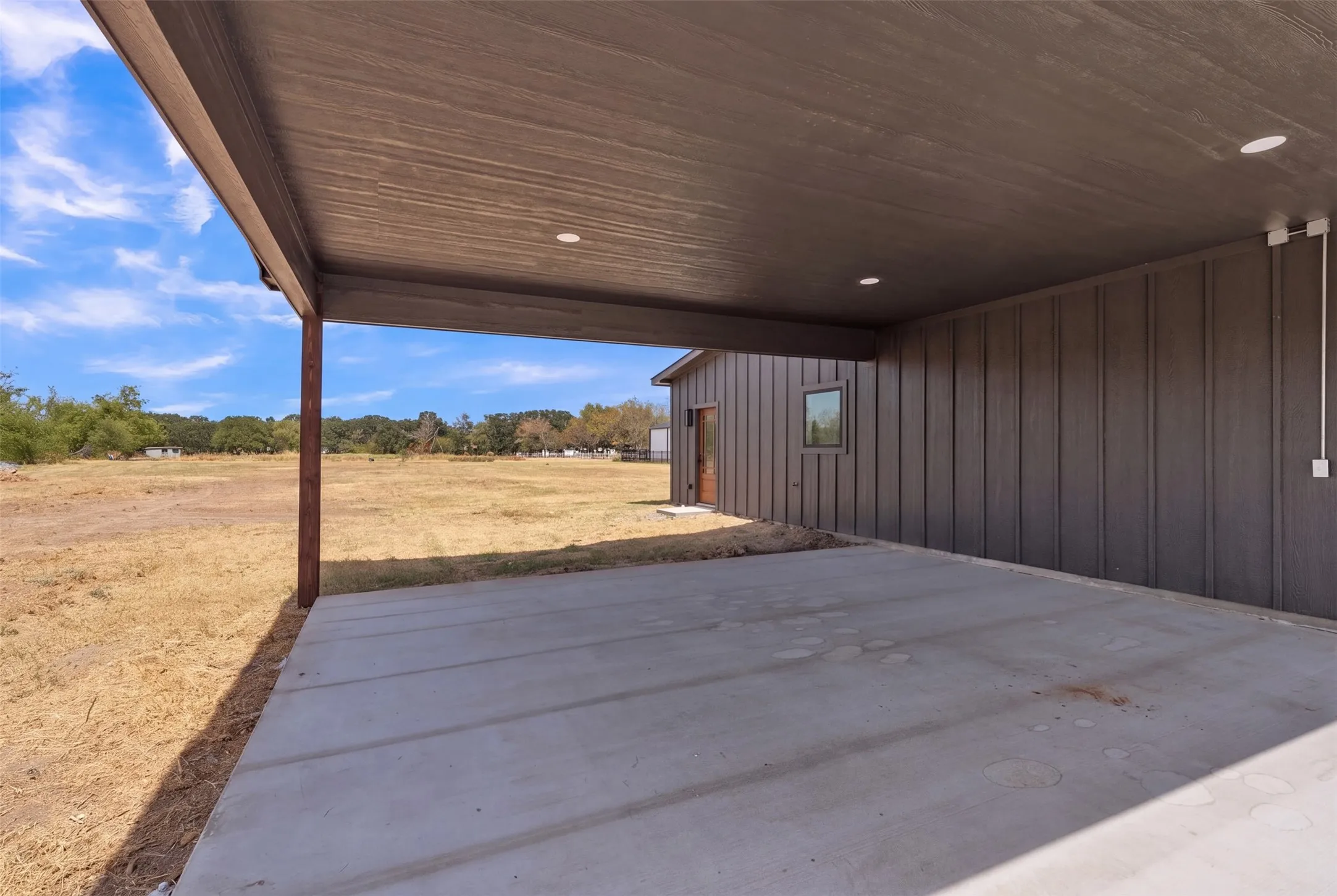 Covered patio with a concrete slab, recessed lighting, and vertical plank siding