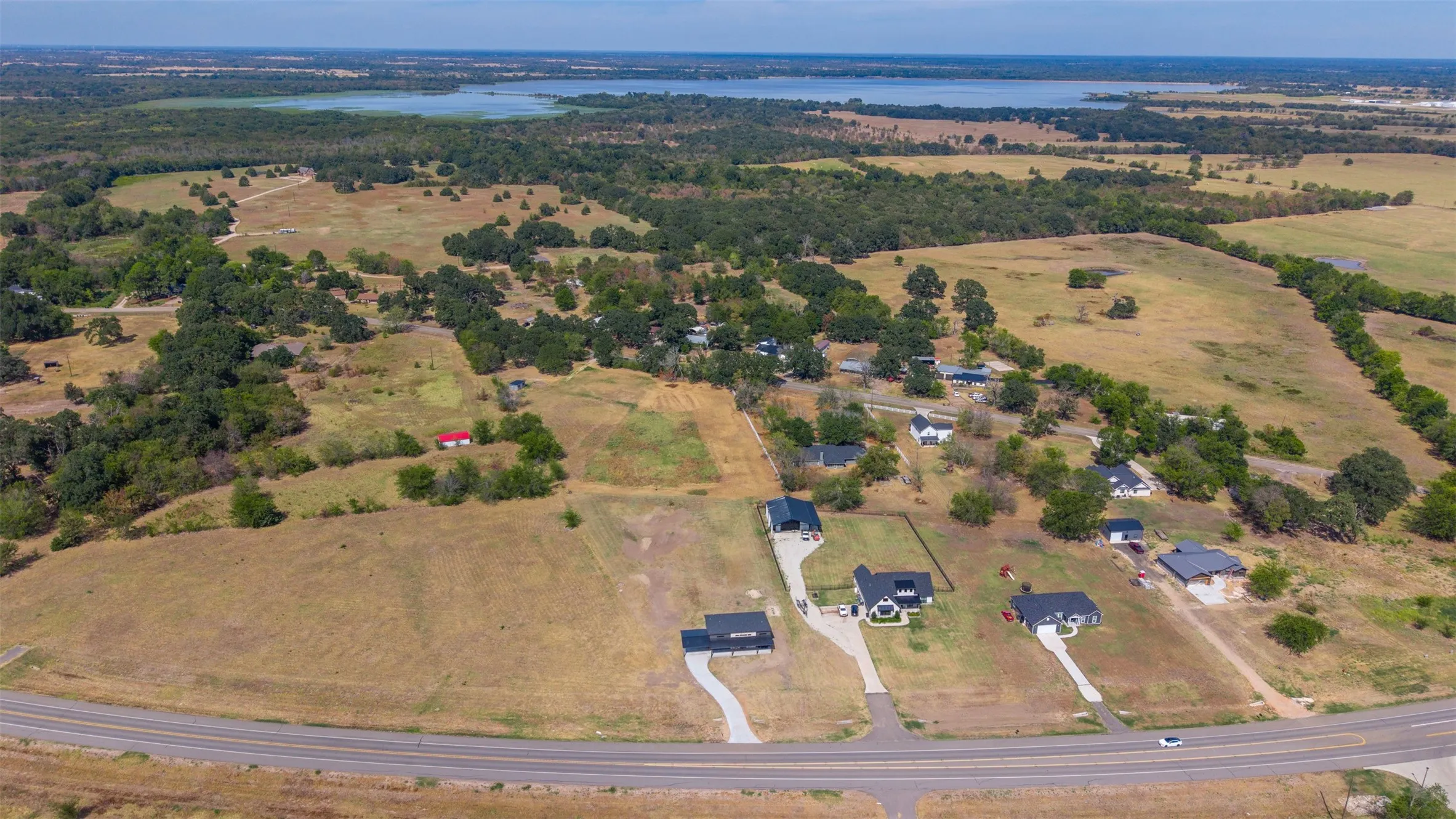 Extensive land parcel featuring multiple residential structures, paved driveways, and proximity to a large body of water