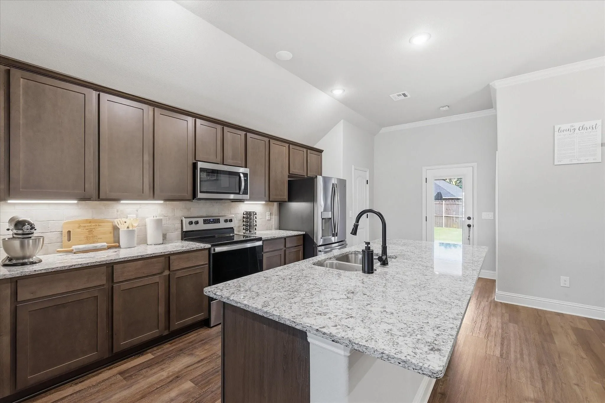 Kitchen featuring wood-finish flooring, recessed lighting, wood cabinetry, stainless steel appliances, and a central island with a sink