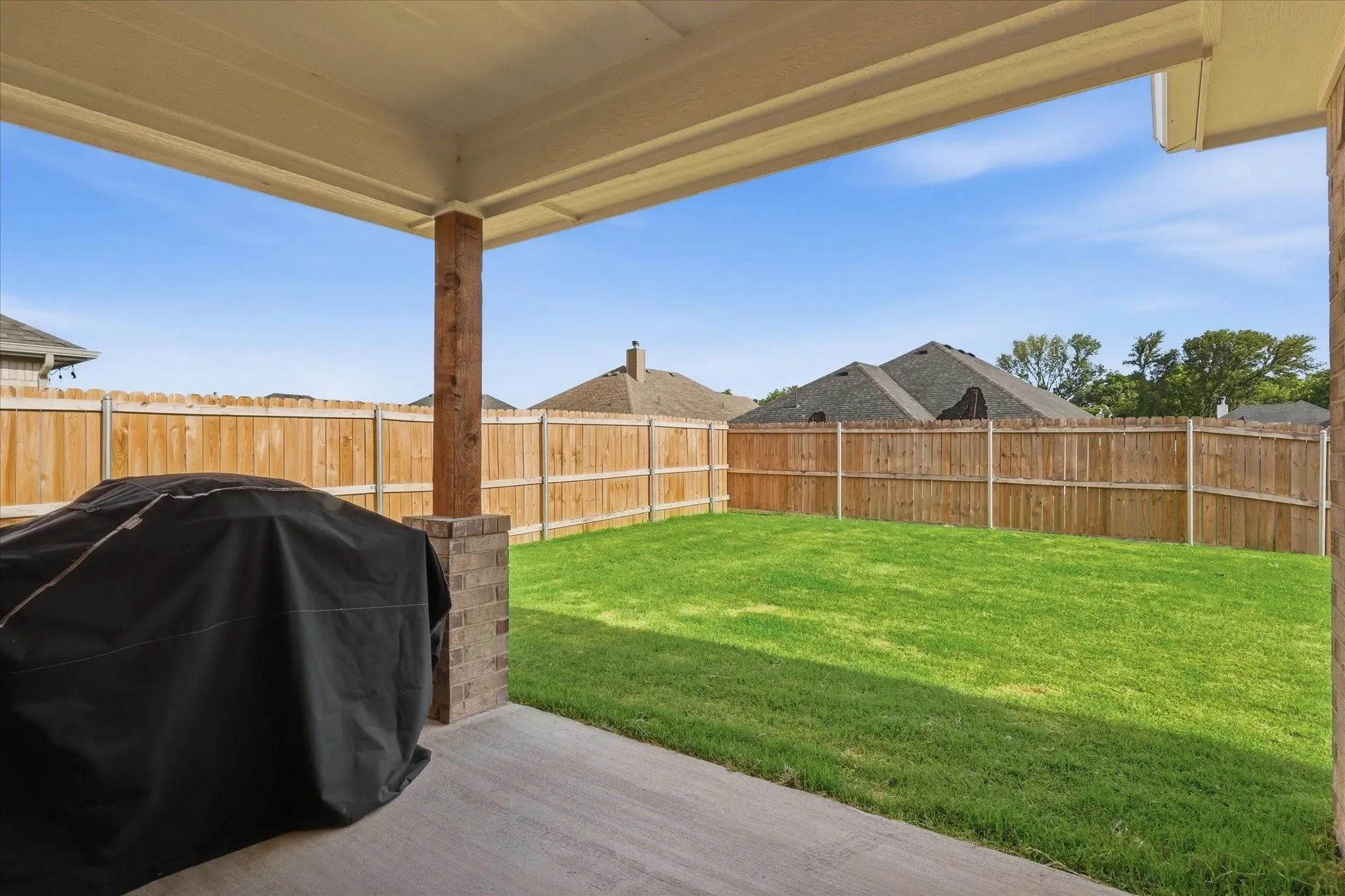 Covered patio with a concrete surface and brick-wrapped columns