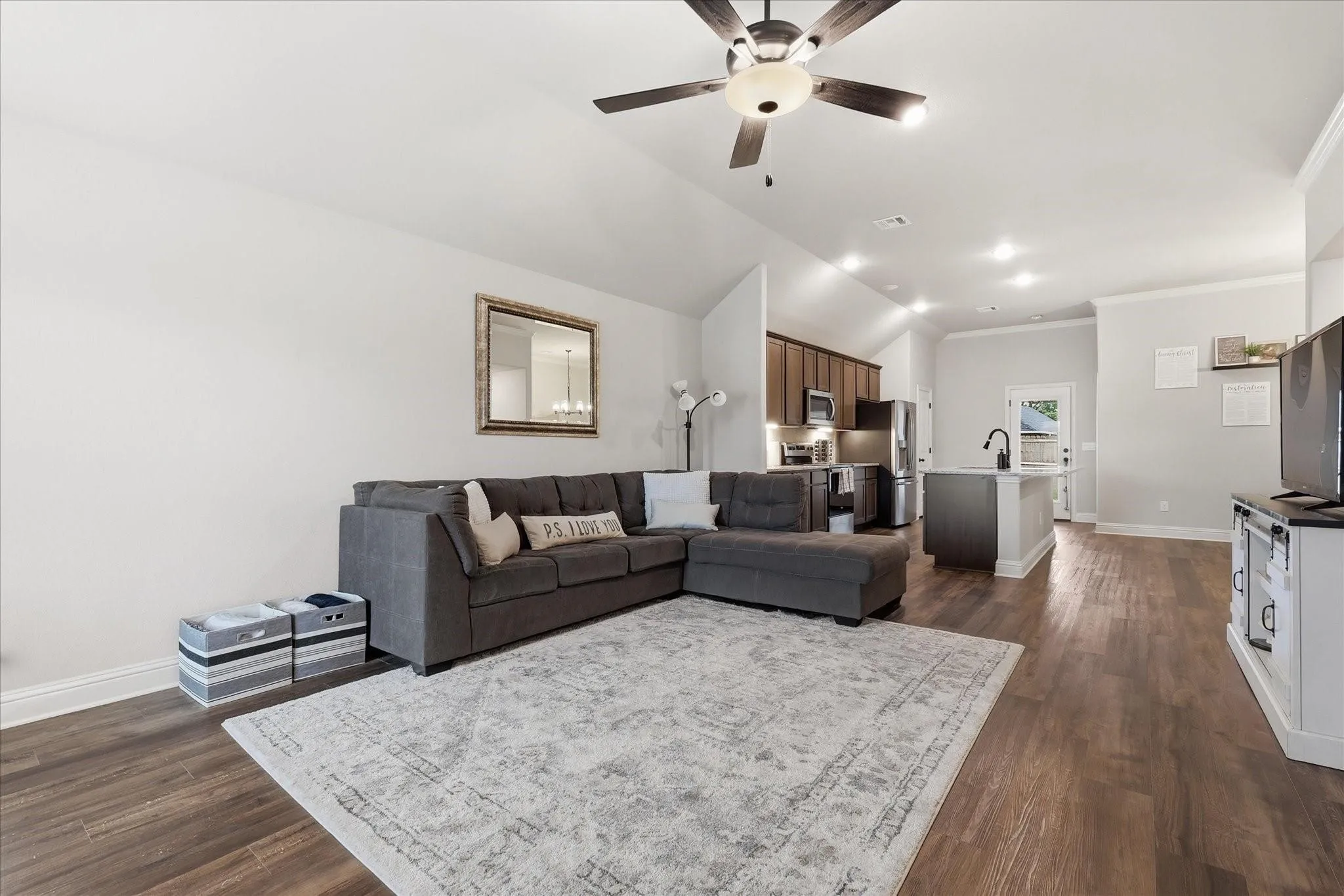 Vaulted ceiling, wood-finish flooring, recessed lighting, ceiling fan light fixture, and a kitchen island with a built-in sink