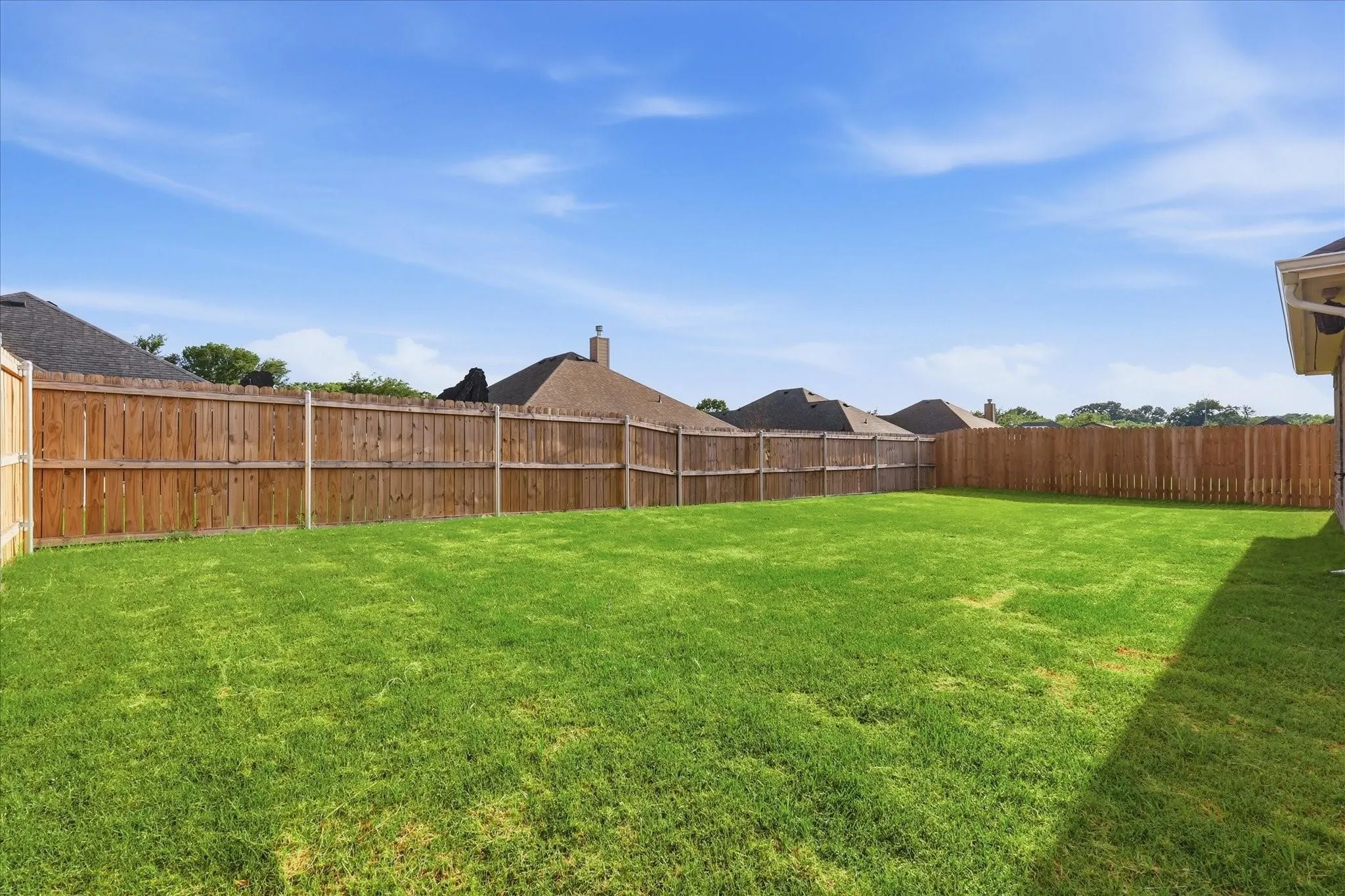 Expansive backyard with a manicured lawn and tall wood privacy fencing