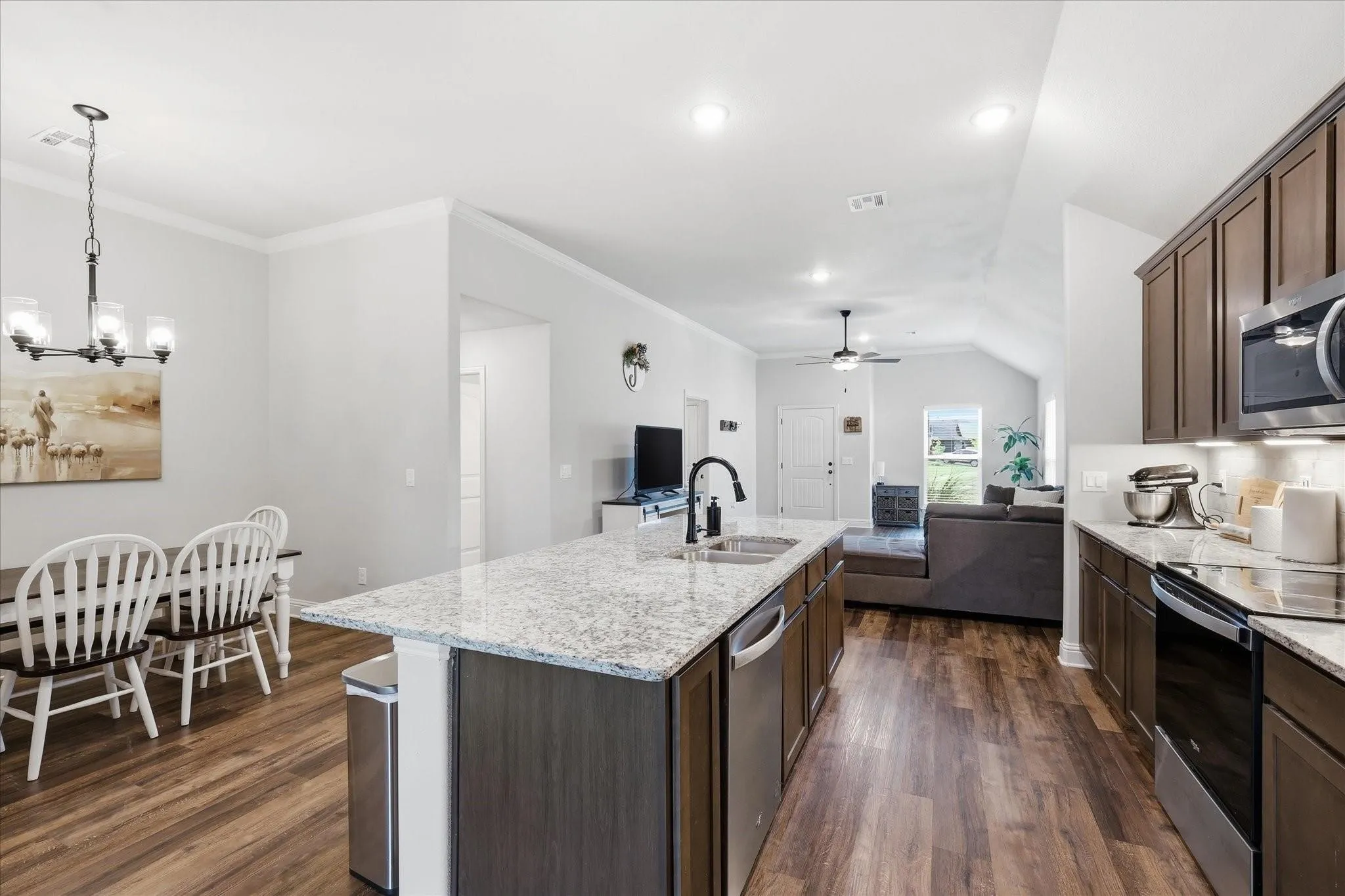 Open-concept kitchen and living area featuring wood-finish flooring, recessed lighting, and a vaulted ceiling